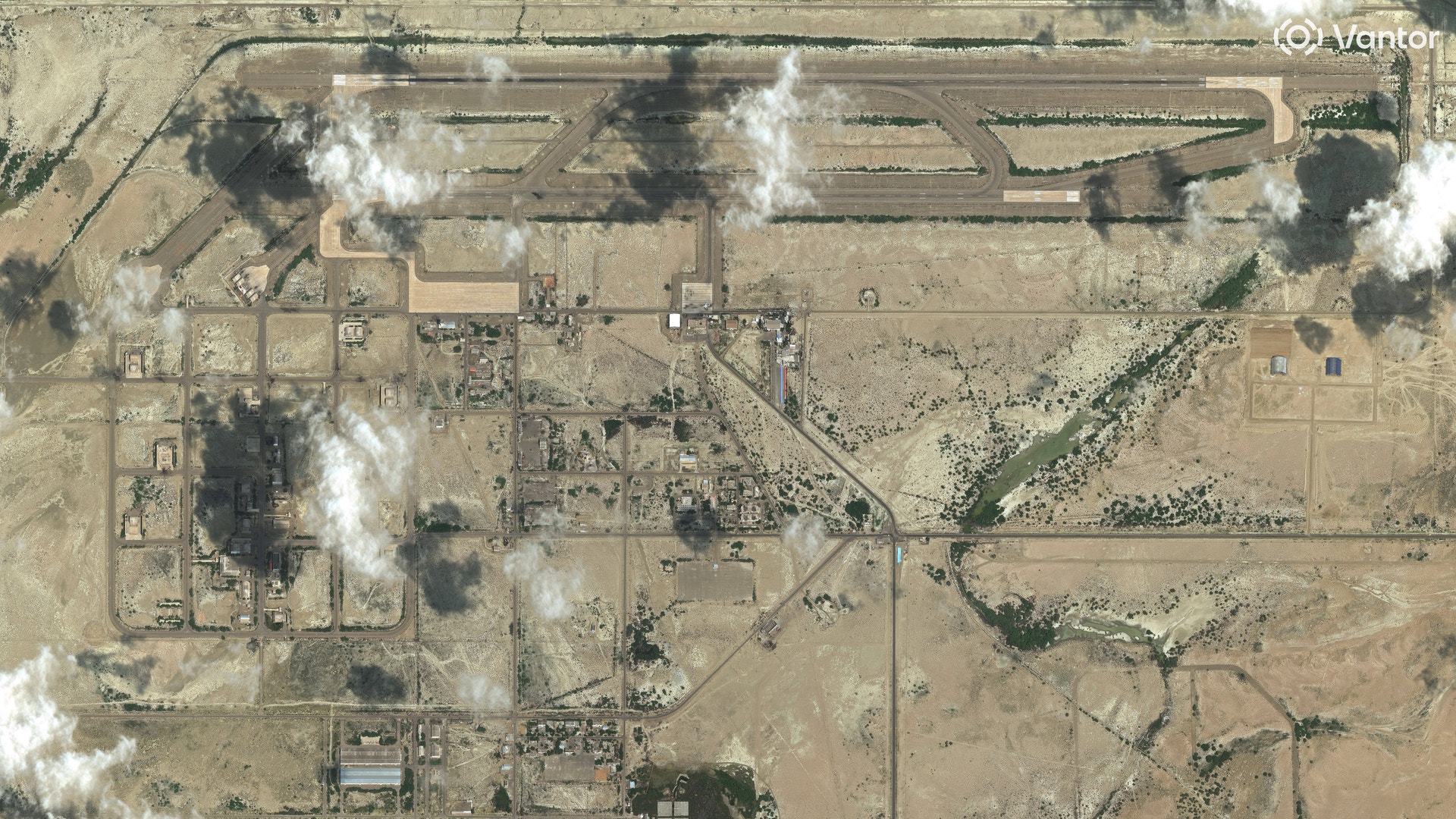 Flygfoto över industrianläggning i ökenlandskap med rökmoln som stiger från fabriksbyggnader