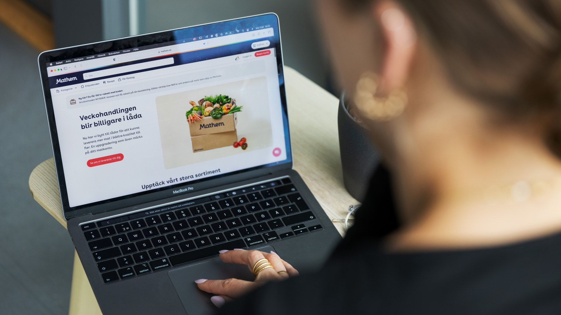 En person använder en laptop och tittar på en webbsida som visar grönsaker i en papperskasse.
