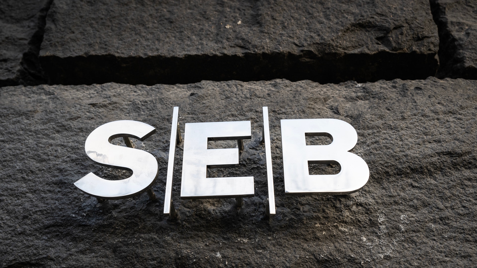 Vita bokstäver som stavar "SEB" på en mörk stenvägga