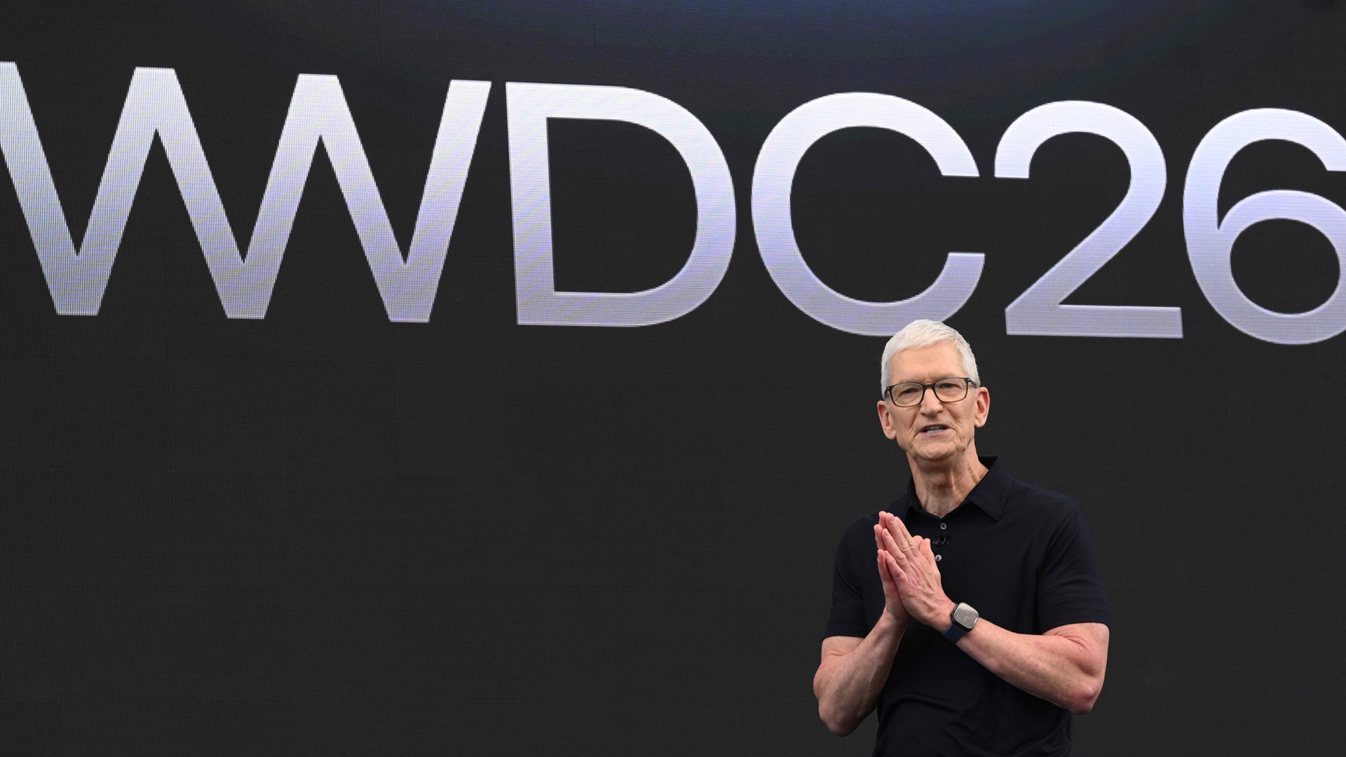 Man i svart skjorta och glasögon talar på en scen framför en stor skärm med texten WWDC26.