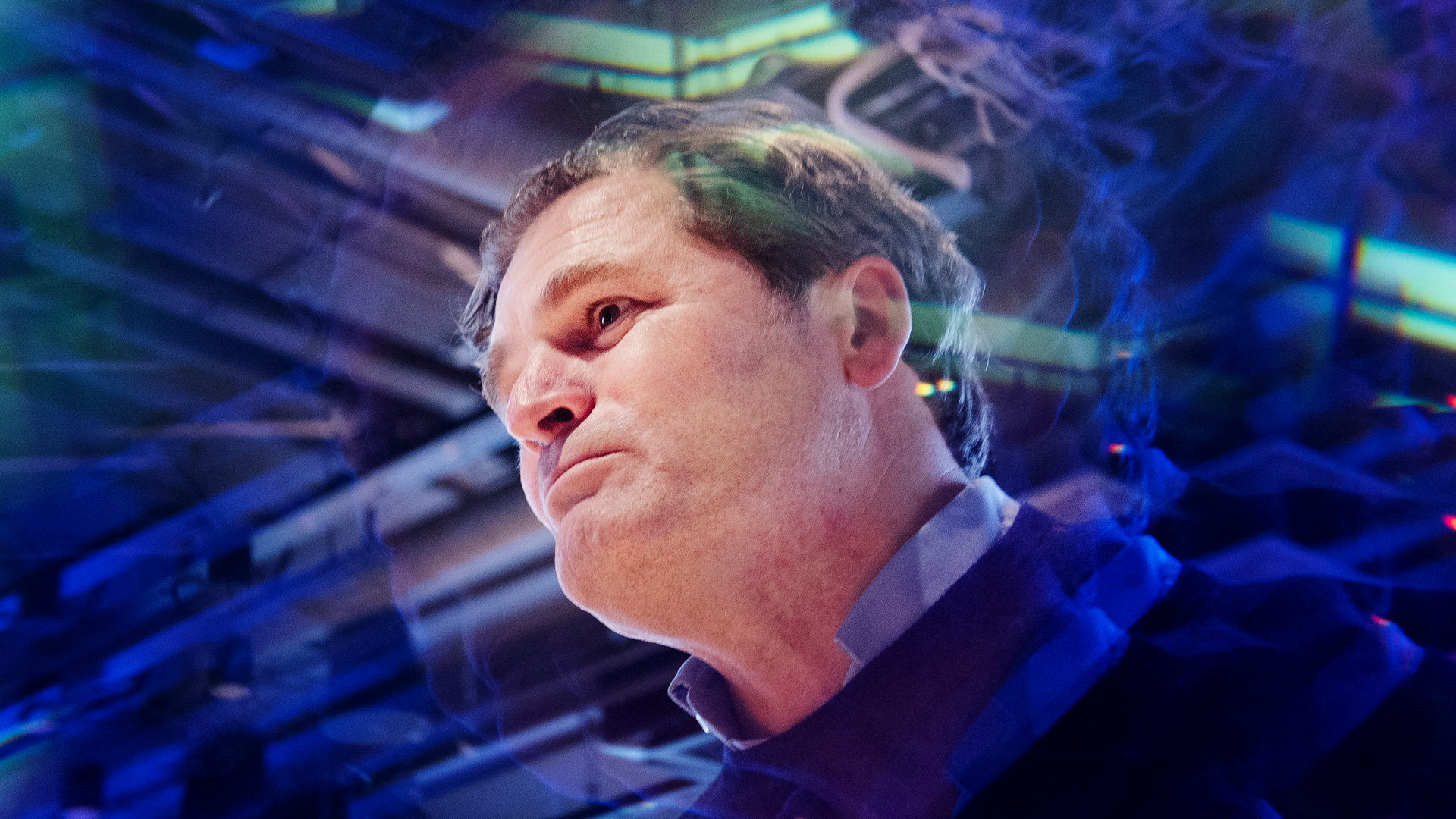 Porträttbild av en man i profil mot en digital bakgrund med blå och gröna teknologiska element. Mannen är avbildad från sidan och ser ut mot höger, mot en suddig bakgrund av digitala kretsar och ljuseffekter.