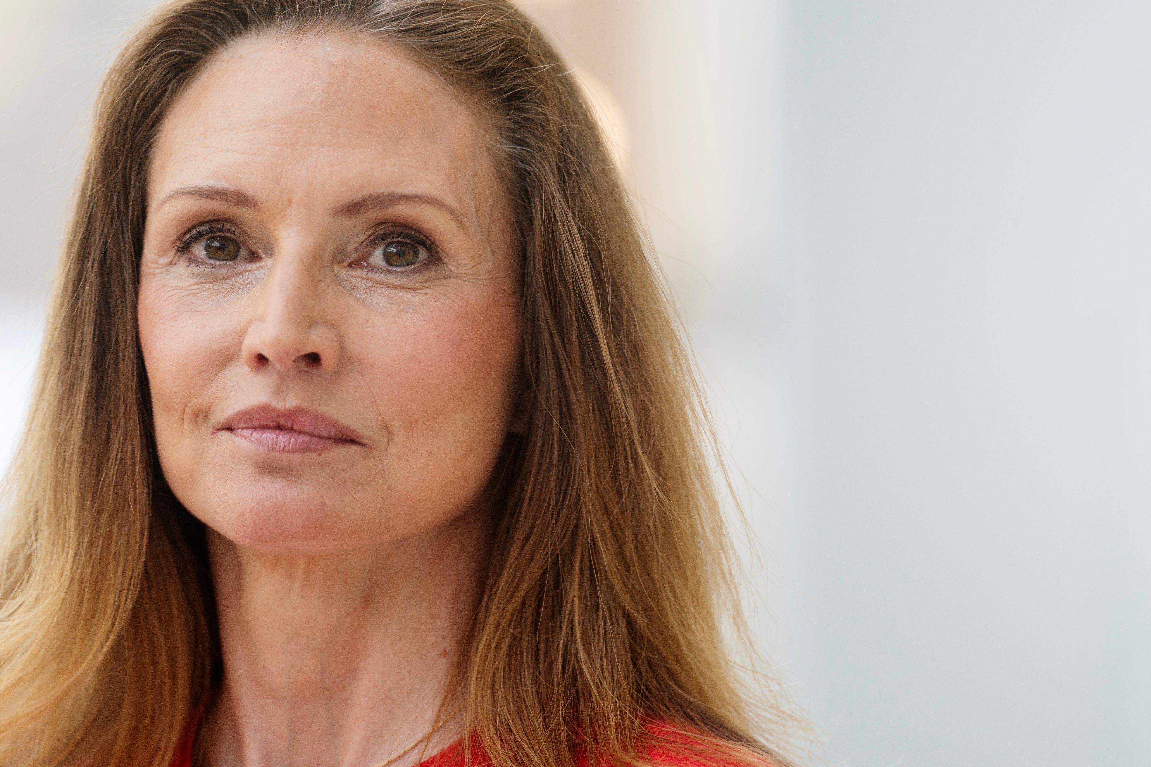Porträtt av Patricia Hedelius, kvinna med långt rödbrunt hår, iklädd röd tröja.