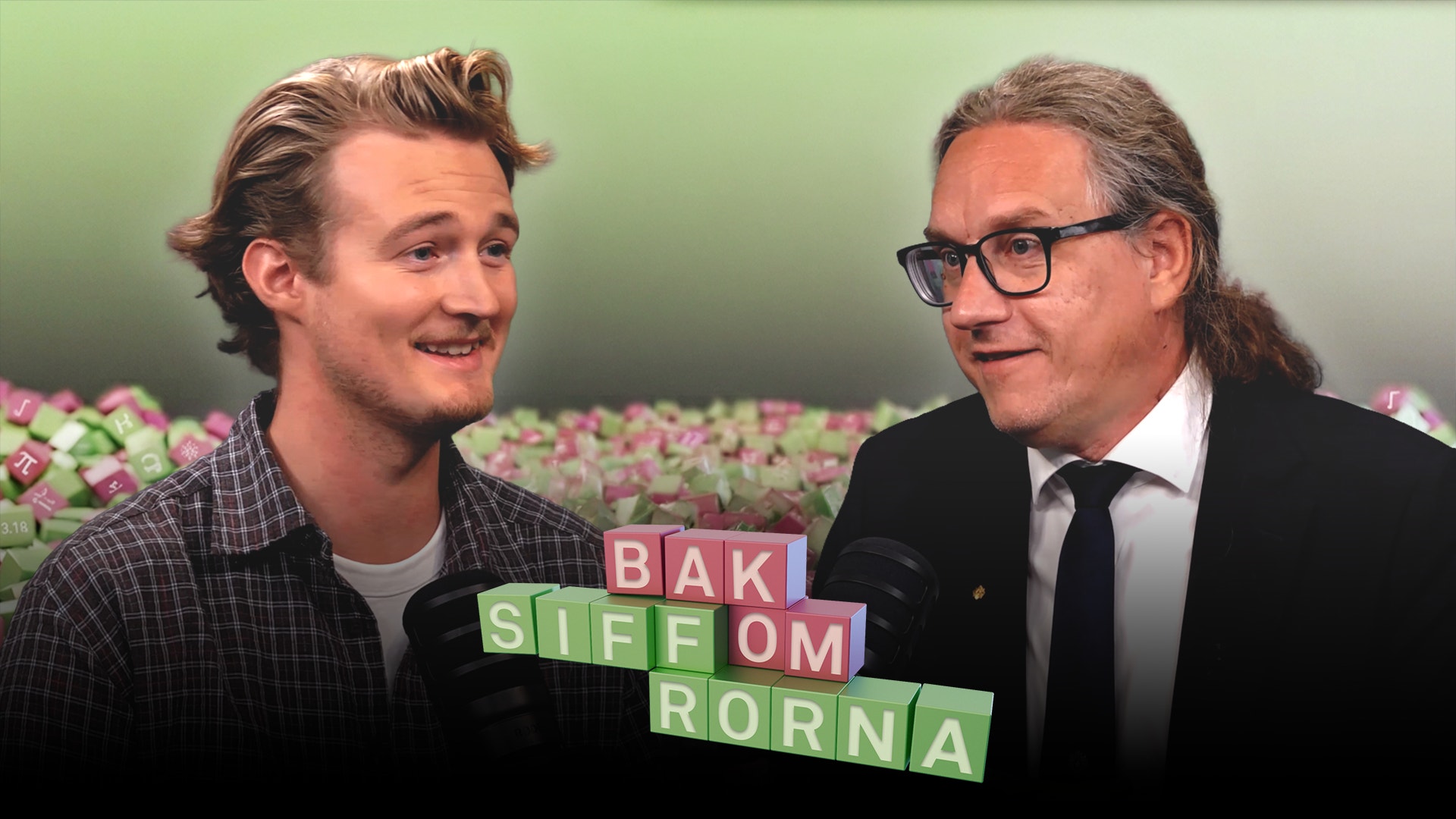 Två leende män i samtal framför en vägg av färgglada klossar. Mellan dem står texten "Bak siffrorna".