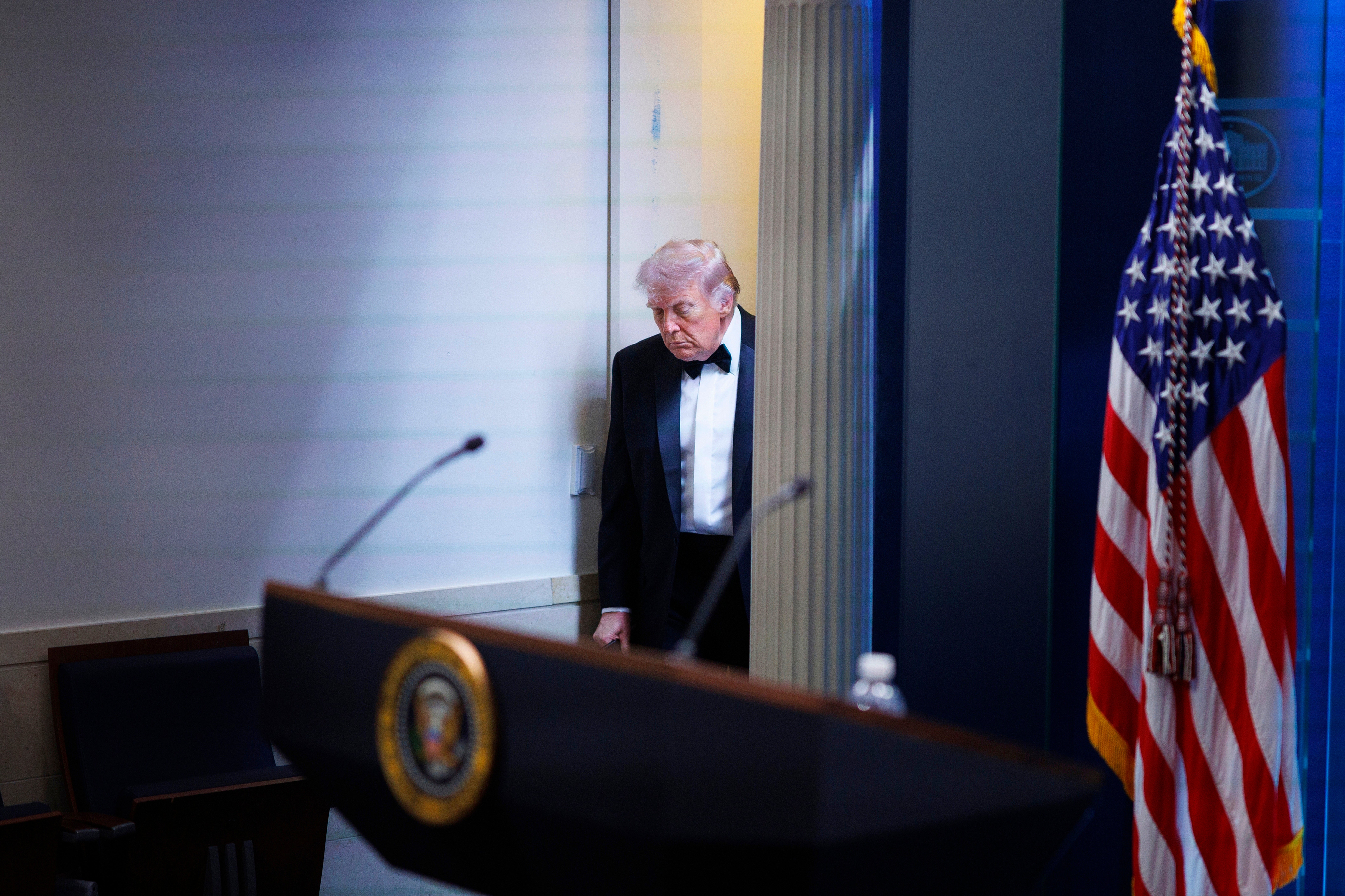 En äldre man i smoking står vid ett podium med presidentens sigill. En amerikansk flagga syns i bakgrunden.