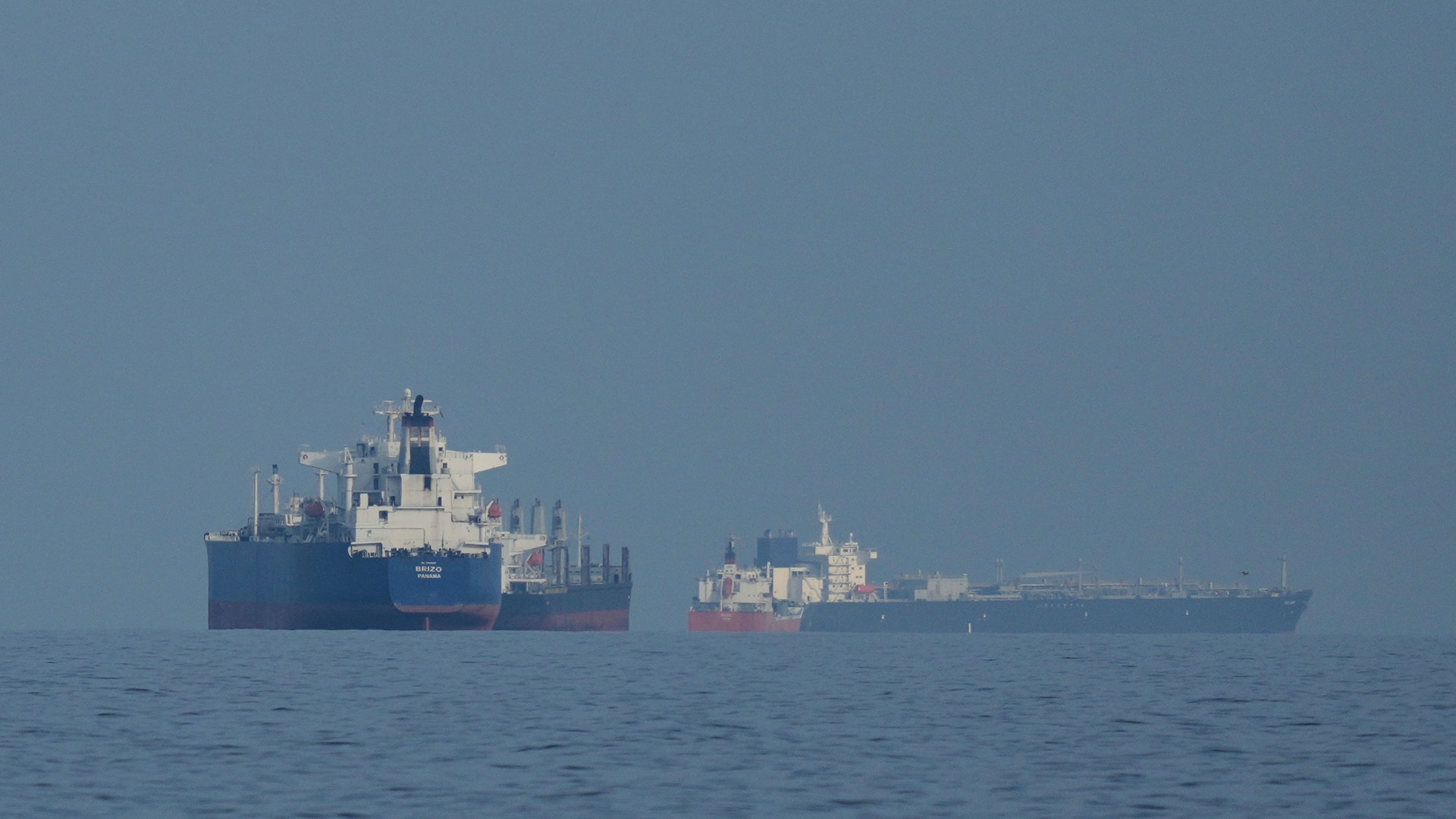 Två stora lastfartyg på öppet hav under klar himmel