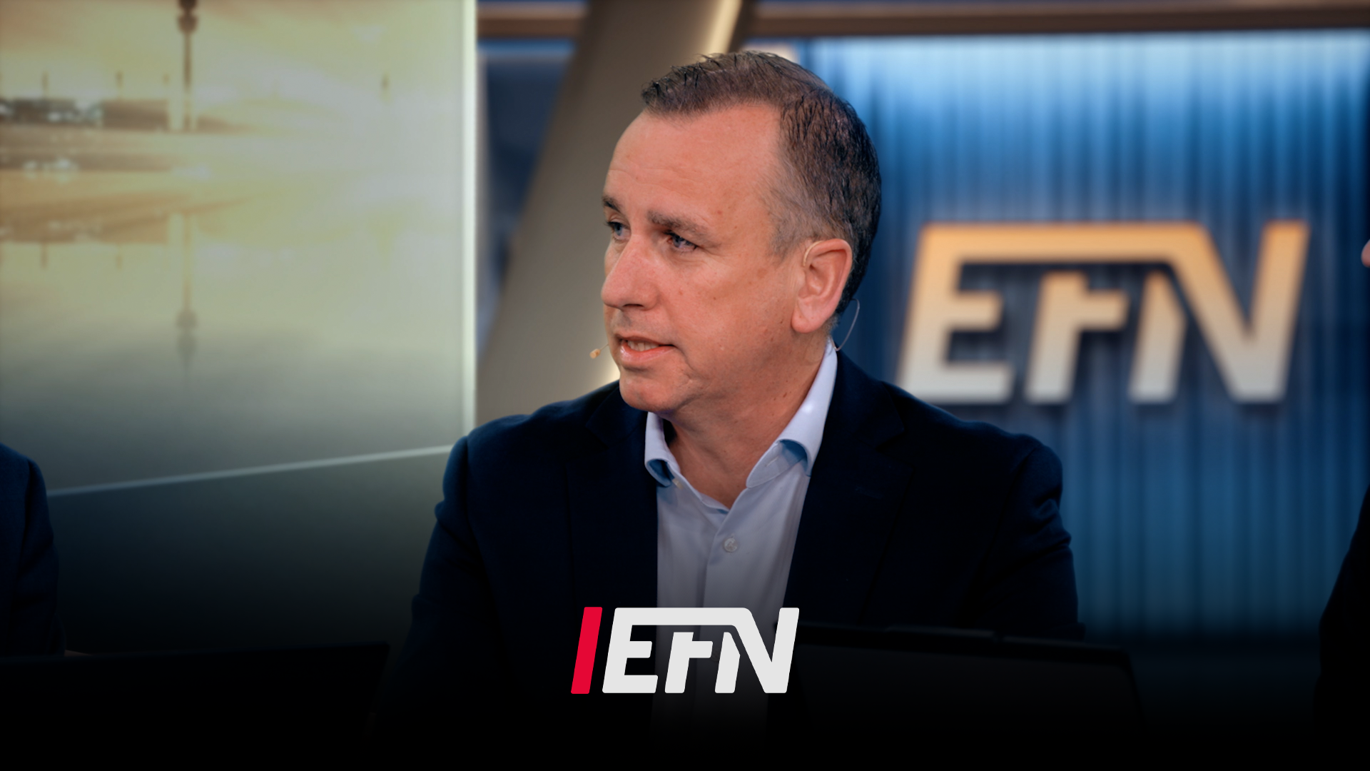 Man i mörkblå blazer sitter i TV-studio under en intervju. EFN-logon syns i bakgrunden.