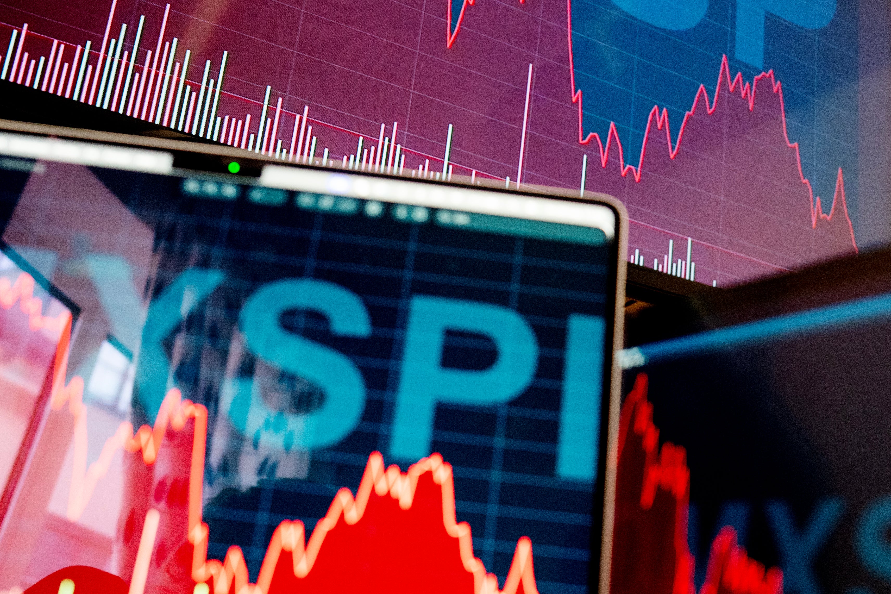 Skärm som visar finansiella grafer och aktiekurser med röda och blå linjer som representerar marknadstrender och prisförändringar.