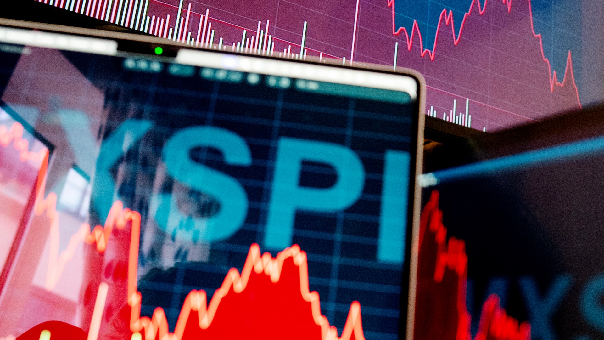 Skärm som visar finansiella grafer och aktiekurser med röda och blå linjer som representerar marknadstrender och prisförändringar.