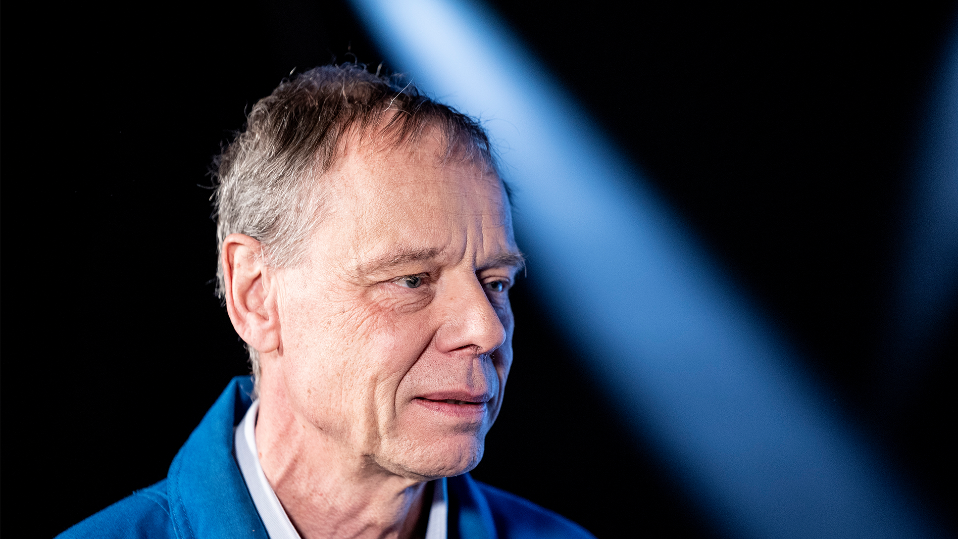 Christer Fuglesang på en pressträff. Han bär en blå overall.