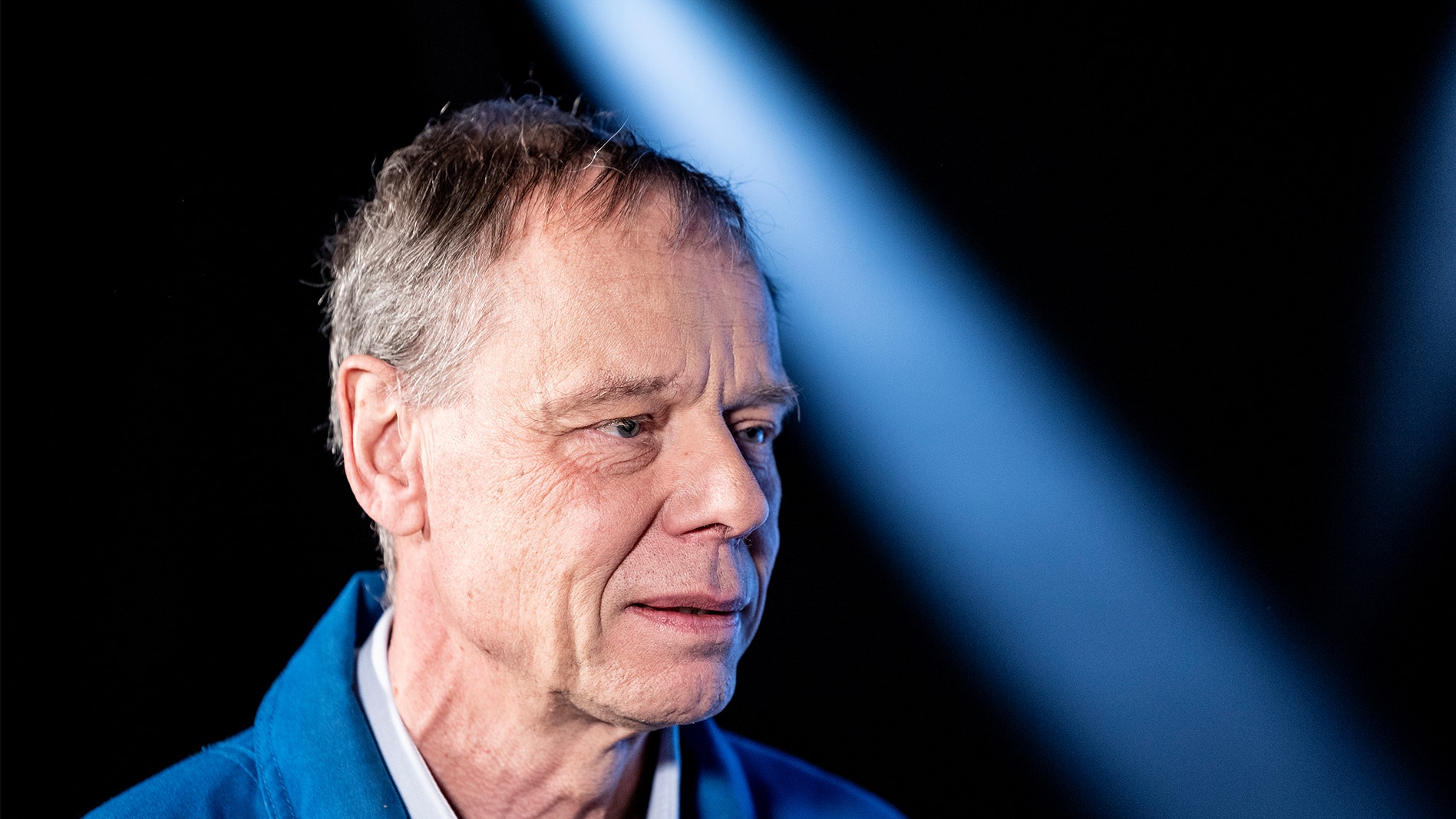 Christer Fuglesang på en pressträff. Han bär en blå overall.