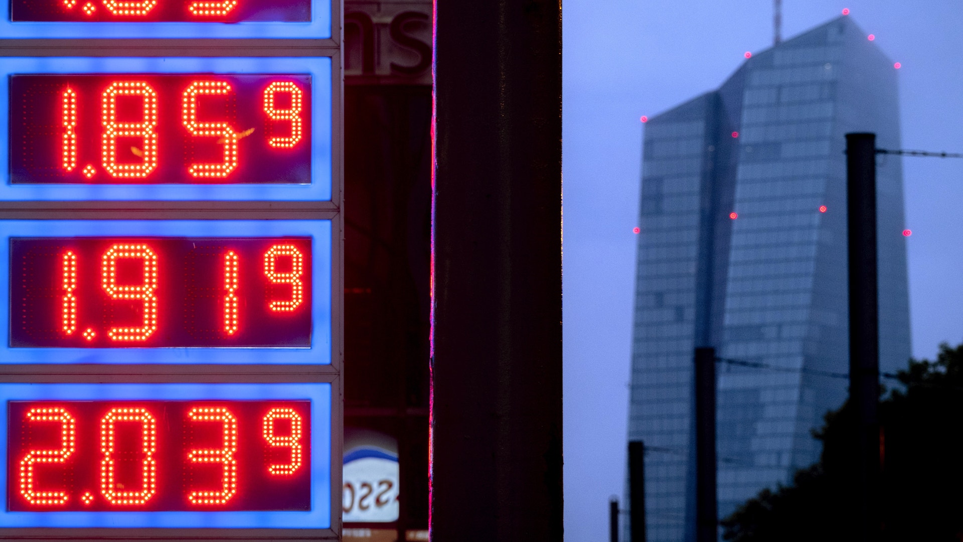 Bensinstation med prisskylt och höghus i bakgrunden