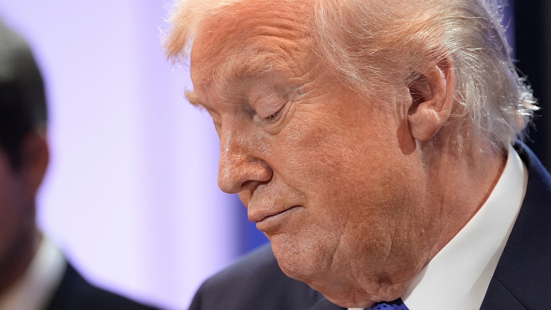 Profilbild av Donald Trump i mörk kostym och blå slips.