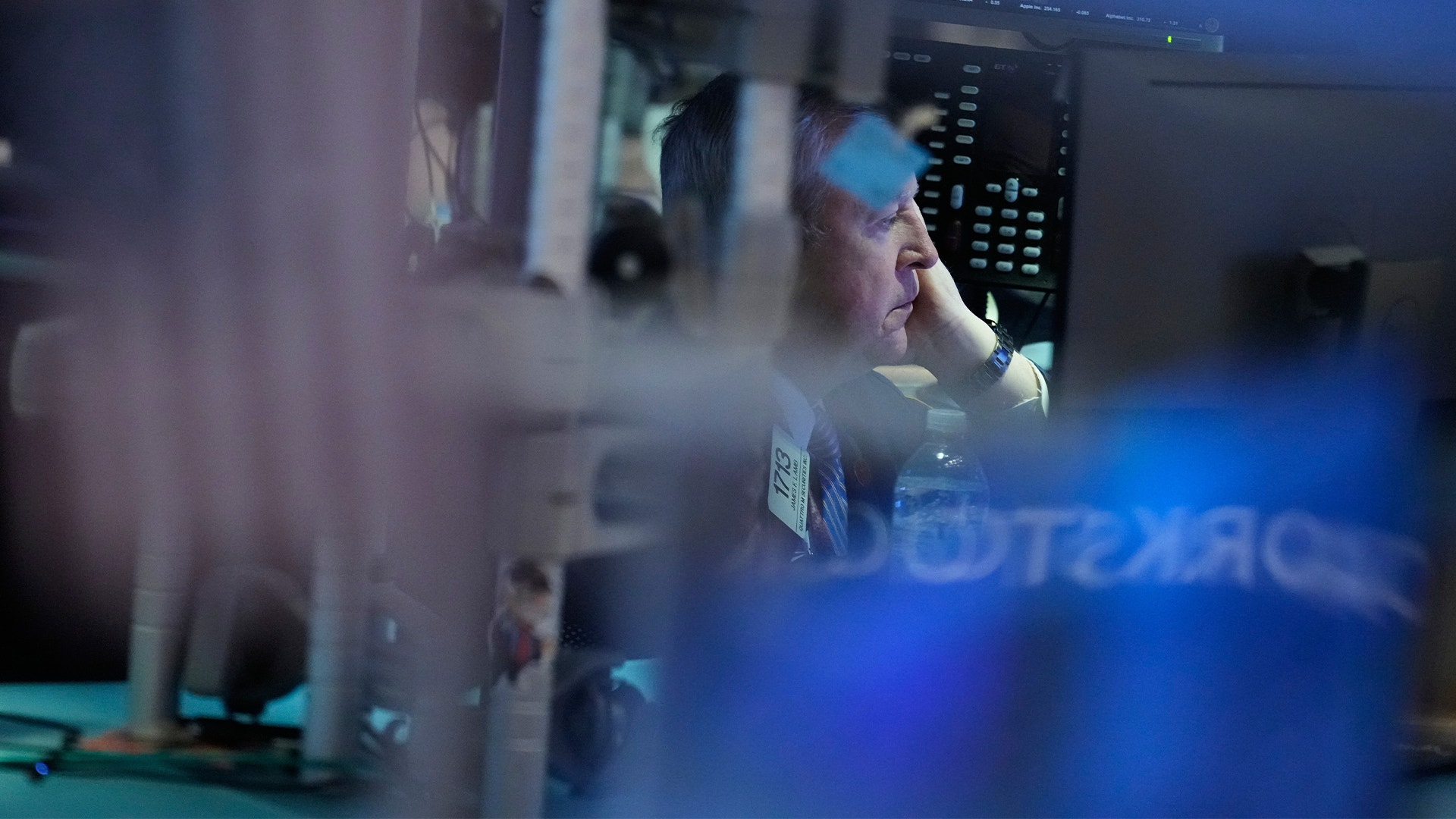 En trader arbetar intensivt vid sina datorskärmar på börsen med finansiell data och grafer.