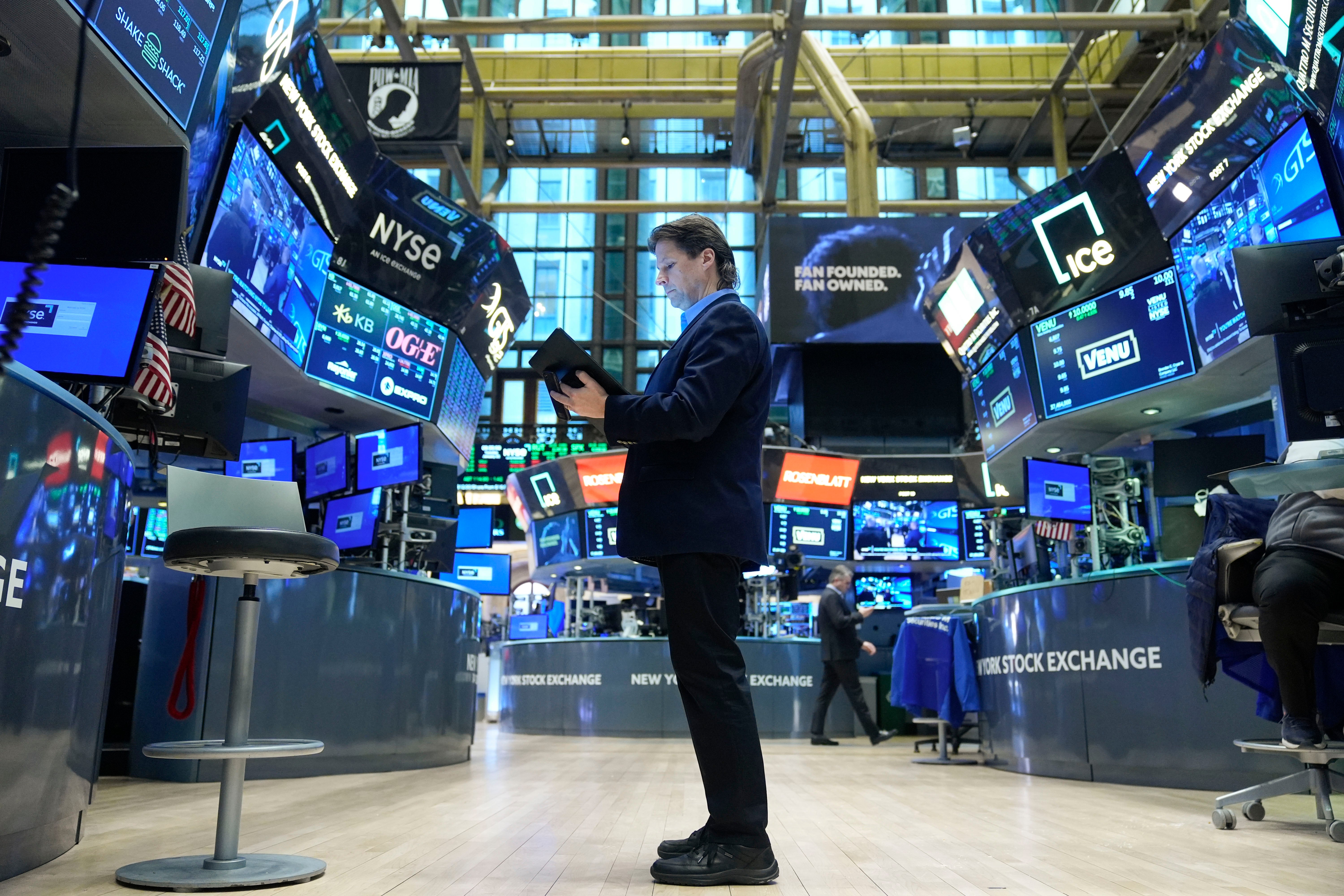 Handlare på en börshandelsplats omgiven av digitala skärmar och handelsstationer.