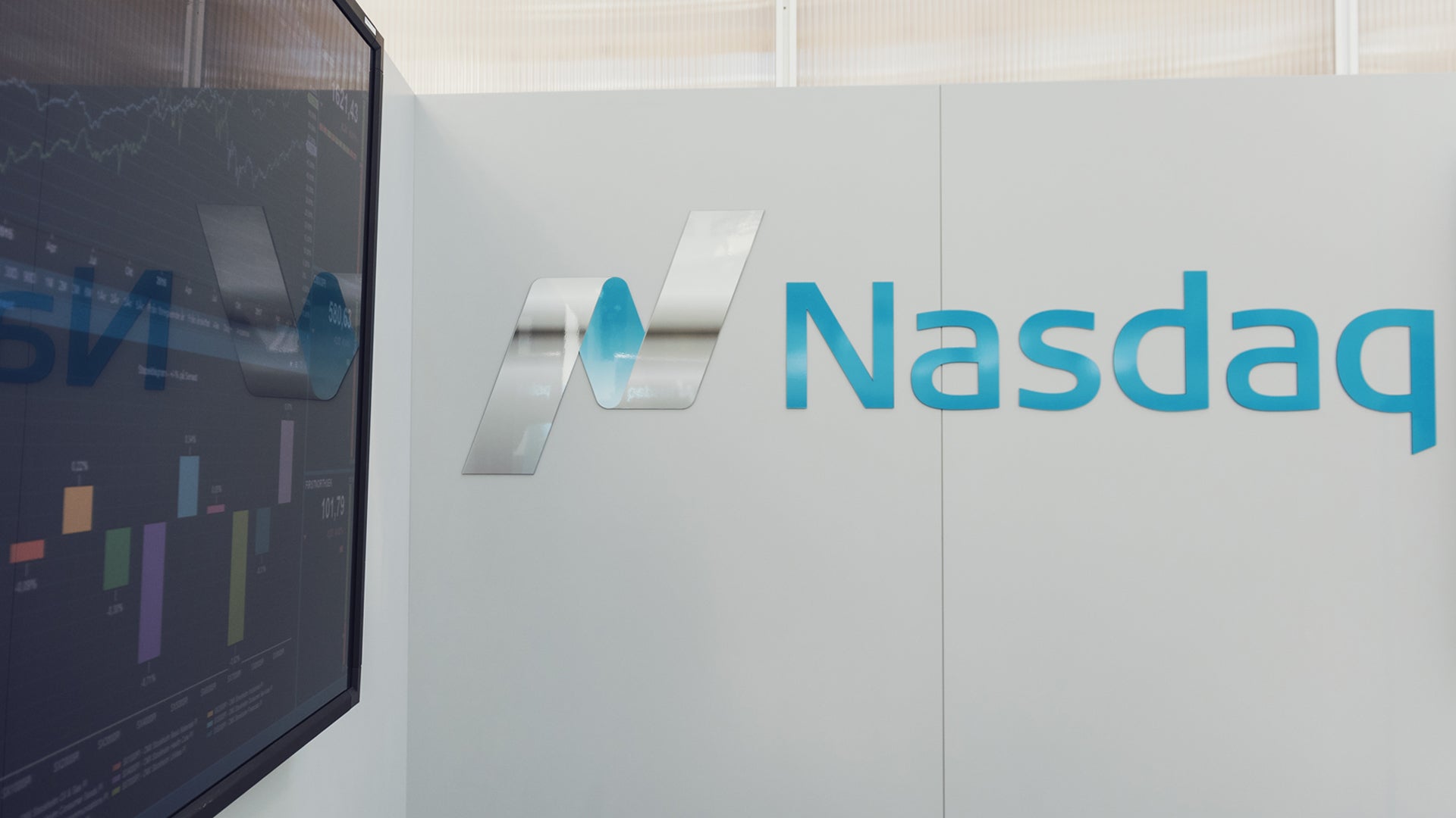 Nasdaq-logotyp på vägg med aktiemarknadskarta i bakgrunden