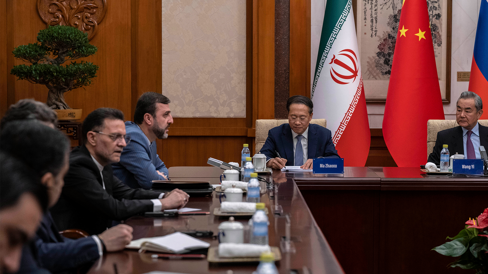 Officiell möte mellan diplomater från Iran, Kina och Ryssland vid ett konferensbord med flaggor från de tre länderna.