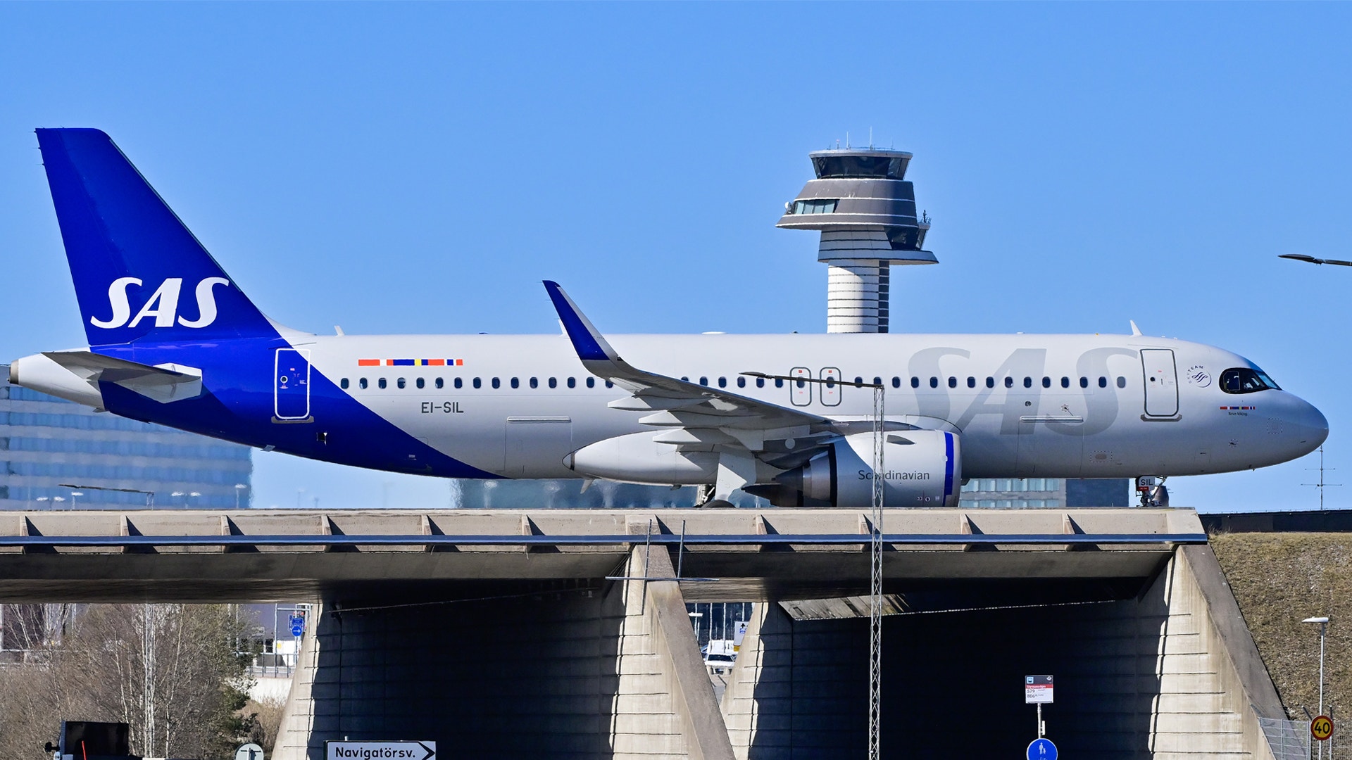 Ett SAS-flygplan parkerat vid en gate på flygplatsen. Flygplanet är vitt med blå detaljer och SAS-logon på stjärten.