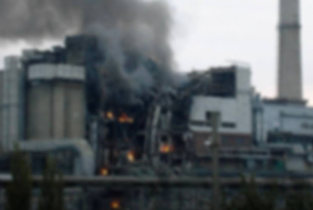 Industrianläggning i brand med flammor och rök som stiger upp från byggnaden.