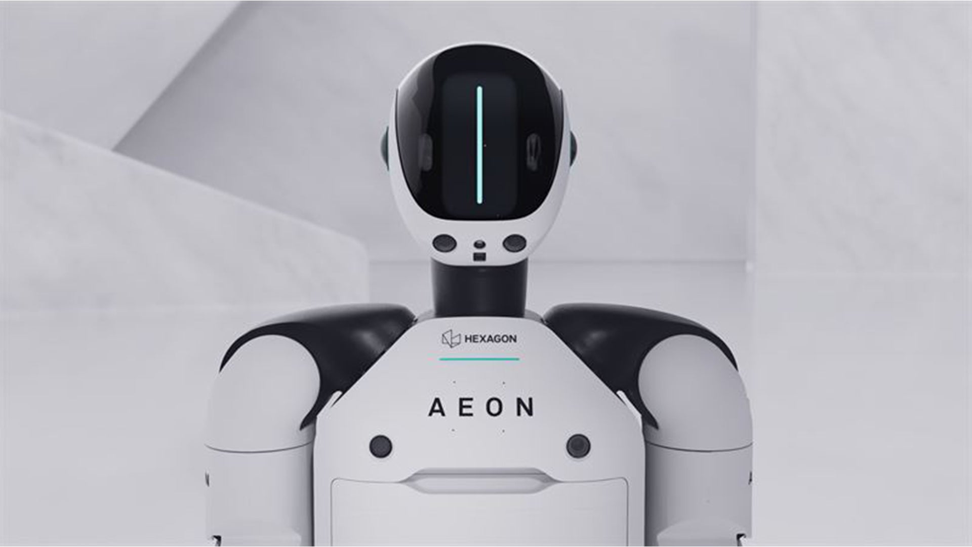 En vit och svart humanoid robot med namnet AEON från Hexagon Robotics. Roboten har ett runt huvud med en digital display och två armliknande strukturer på sidorna.