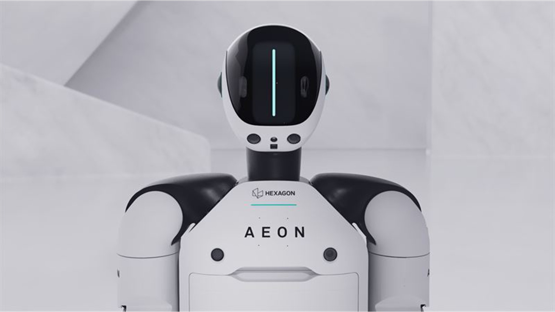En vit och svart humanoid robot med namnet AEON från Hexagon Robotics. Roboten har ett runt huvud med en digital display och två armliknande strukturer på sidorna.