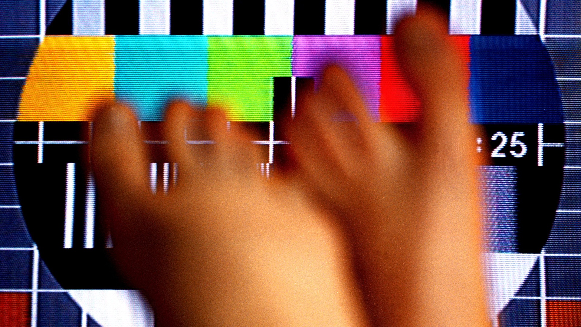 En hand framför en färgkalibreringstavla med färgstaplar och testmönster.