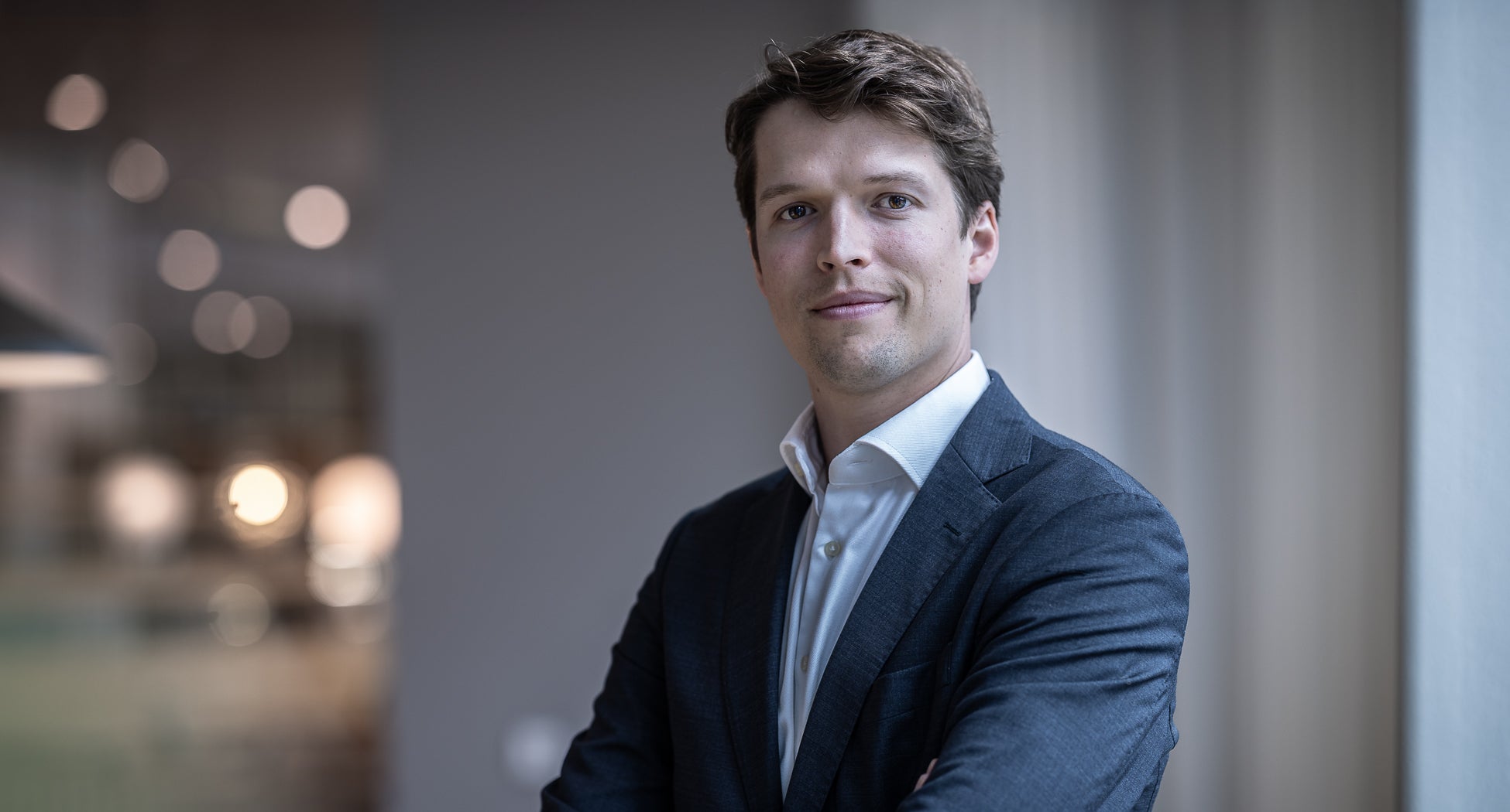 Porträttbild av en man i kostym som ler mot kameran, fotograferad inomhus.