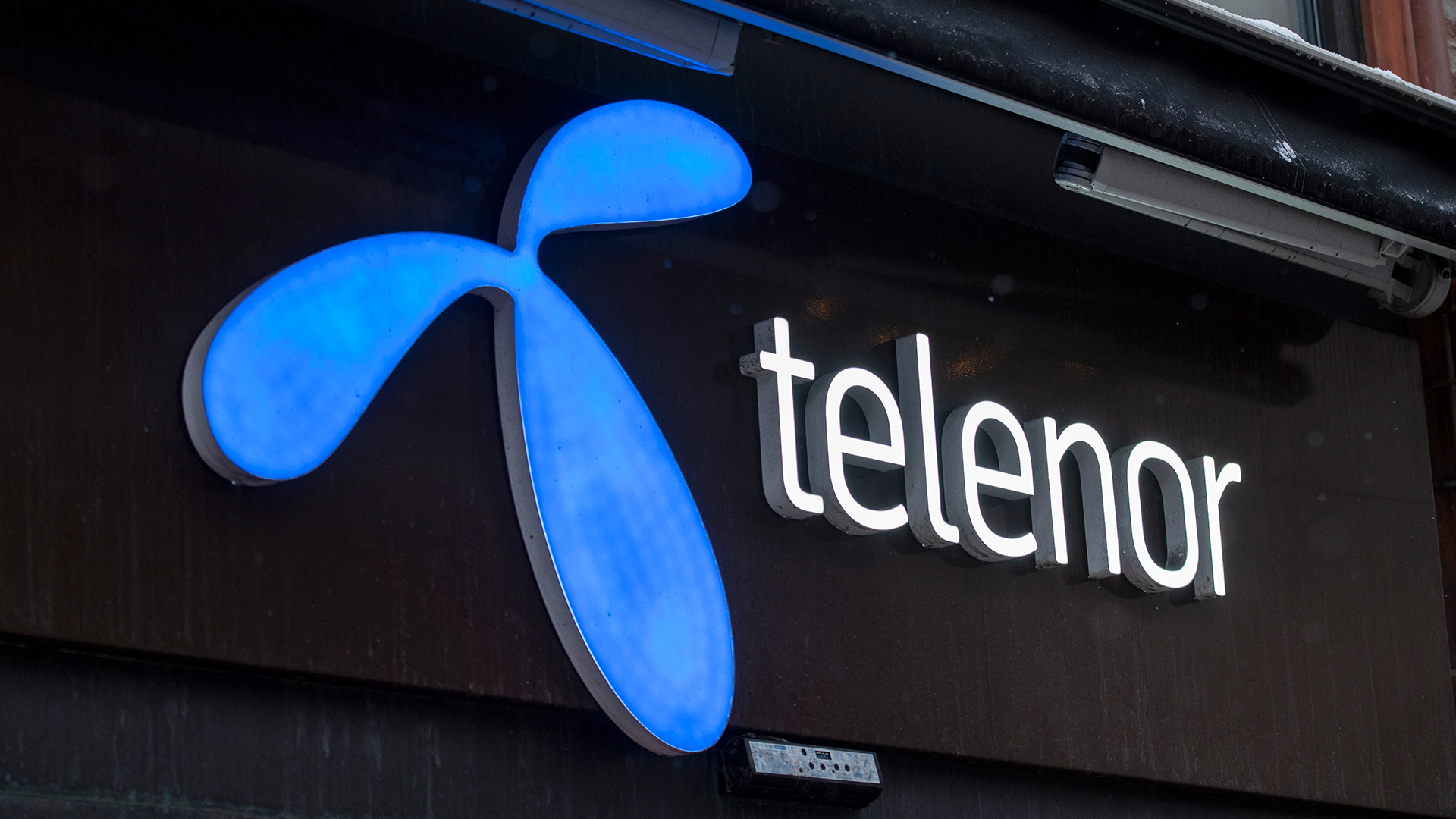 Telenor logotyp på en svart skylt med blå belysning