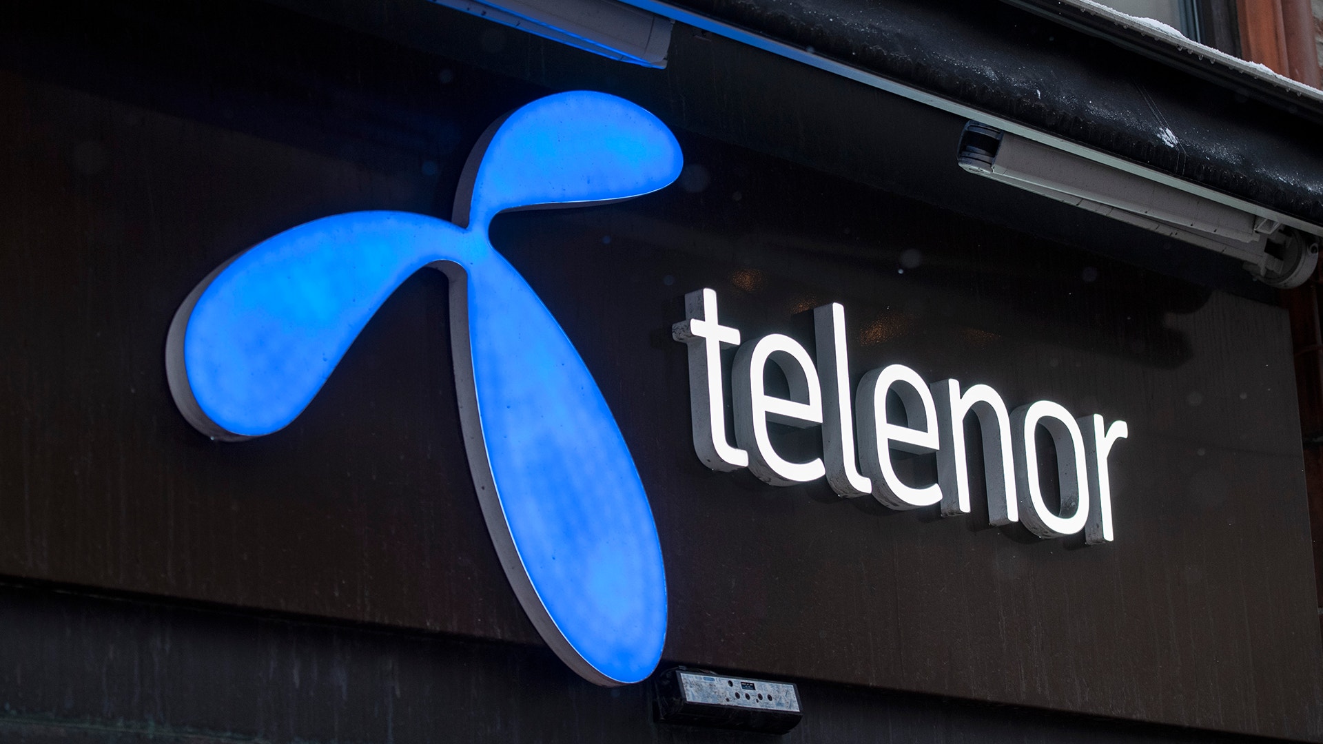 Telenor logotyp på en svart skylt med blå belysning