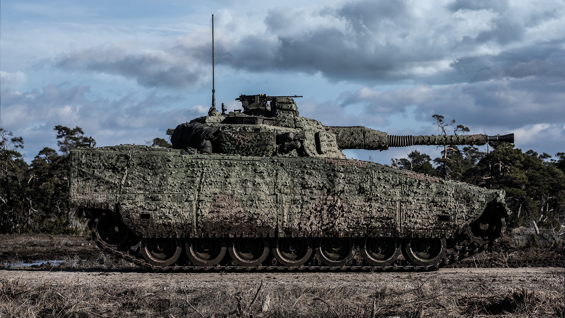 Militär stridsvagn med kamouflage i öppen terräng