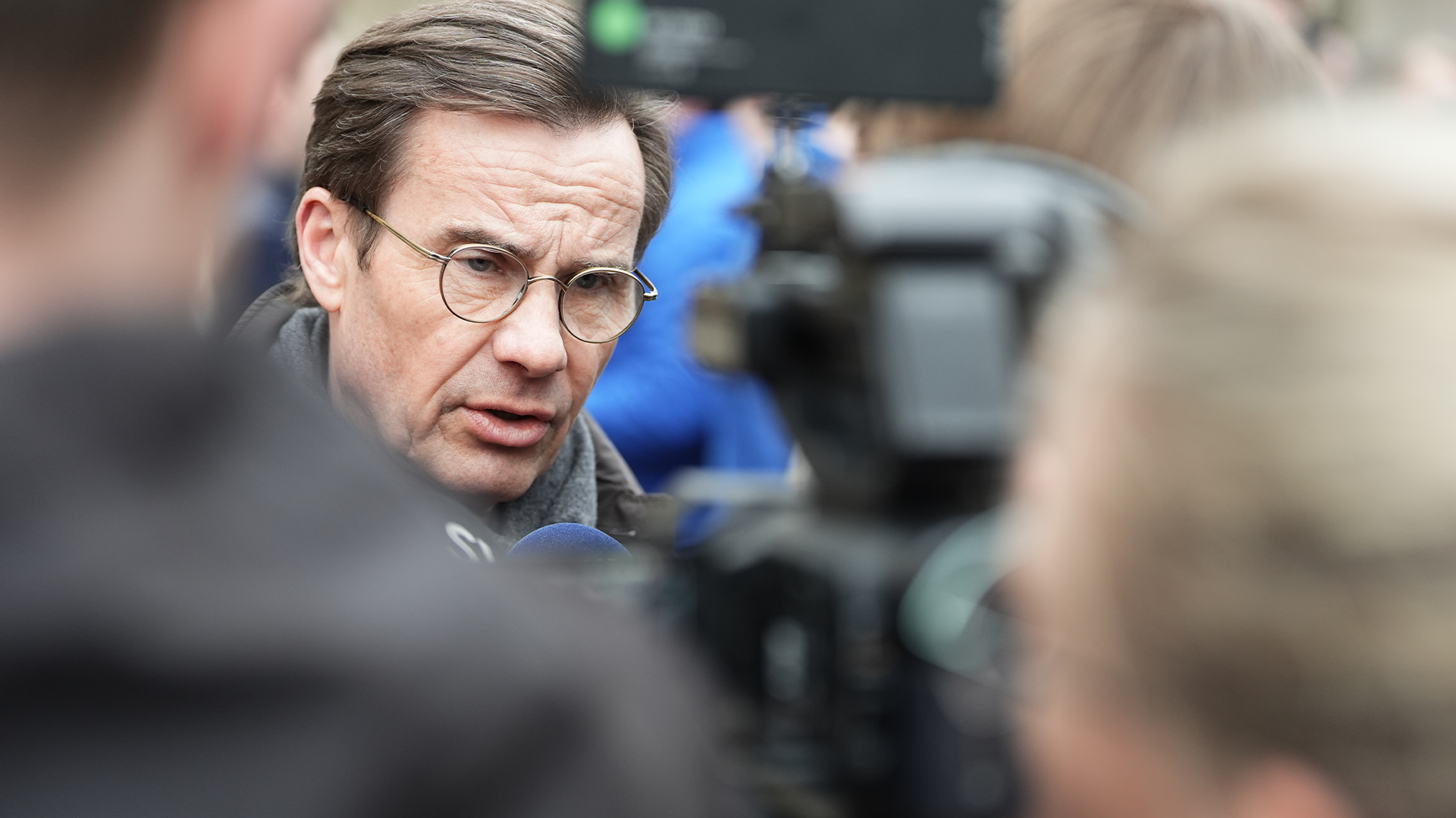 Porträttfoto av en man med glasögon i en offentlig miljö.