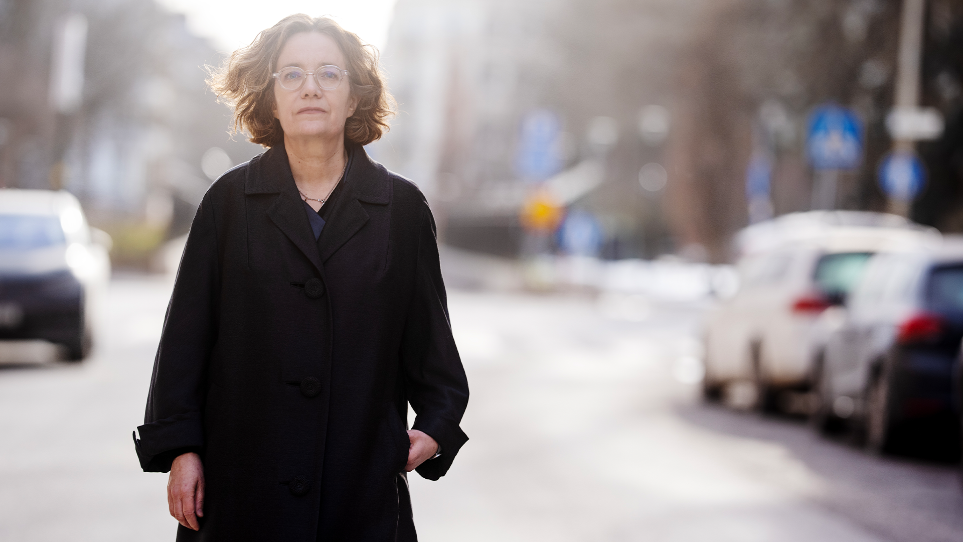 Porträttfoto av en kvinna i svart kappa som står på en stadsgata