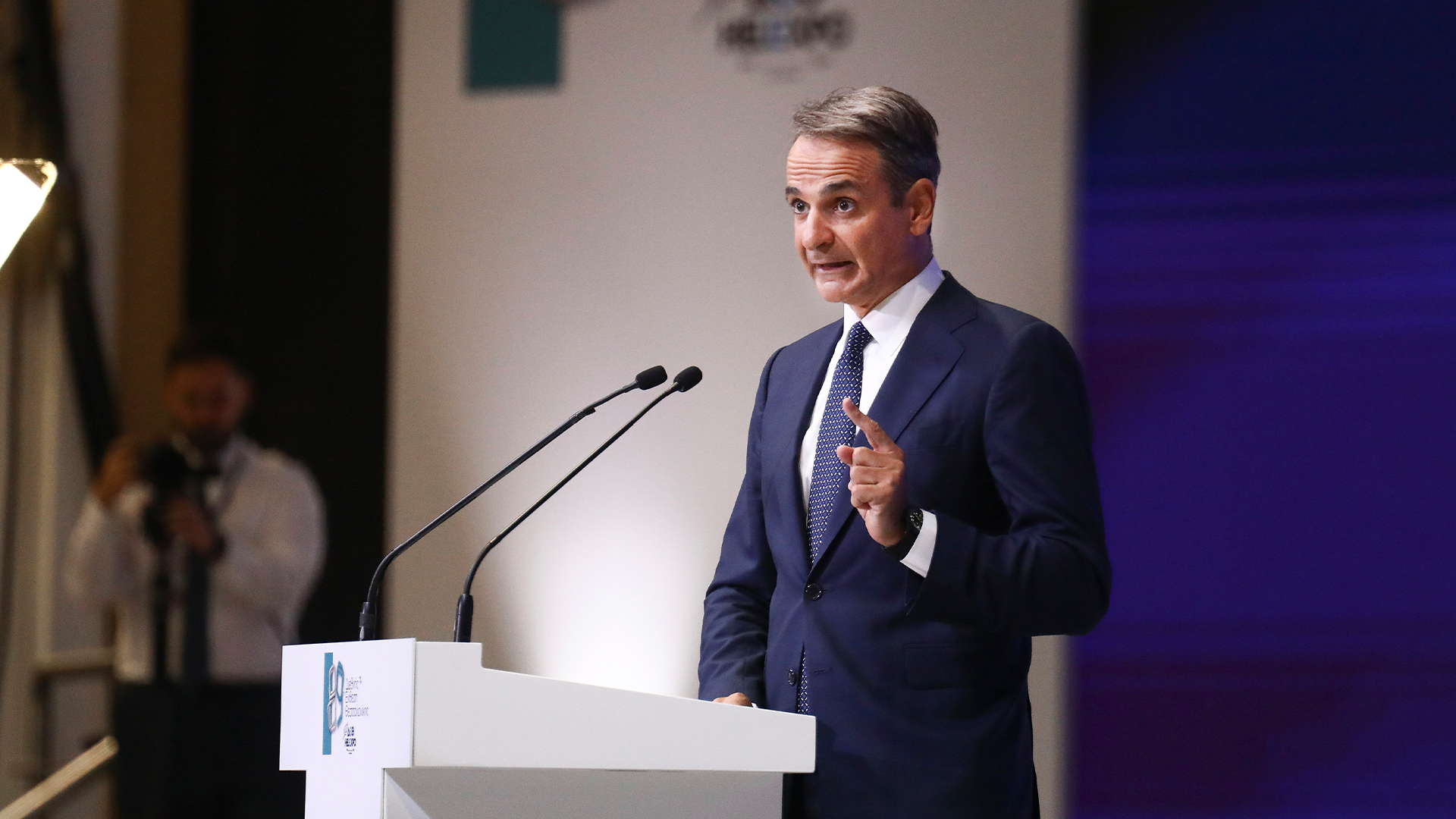 Man i mörk kostym talar vid ett podium under en presentation