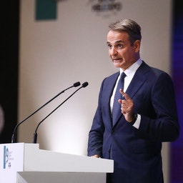 Man i mörk kostym talar vid ett podium under en presentation