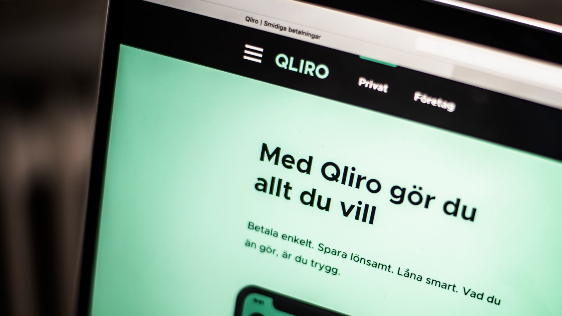 Datorskärm som visar Qliros webbplats med rubriken "Med Qliro gör du allt du vill" på en grön bakgrund.