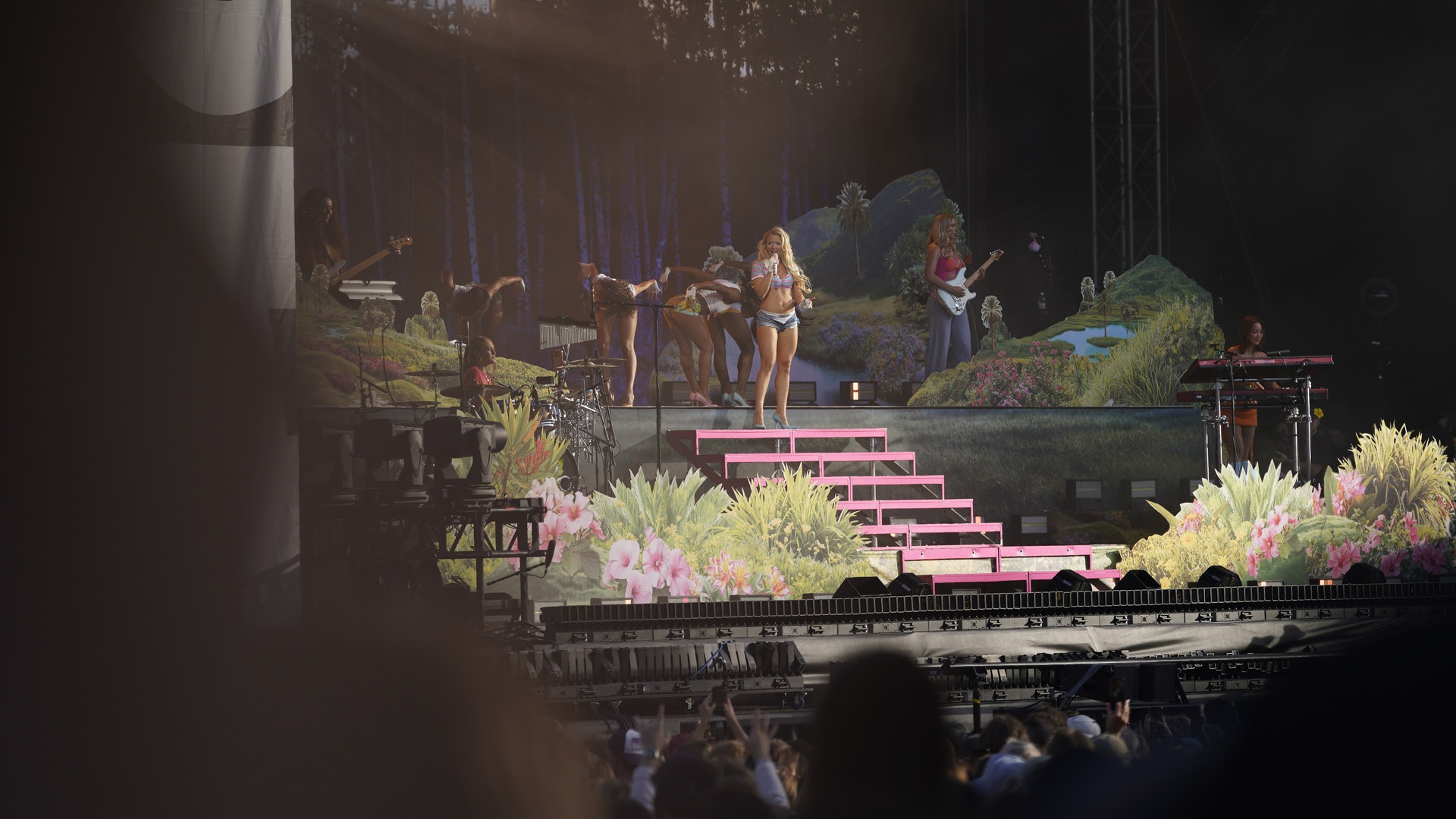 Zara Larsson uppträder på scenen under Way Out West-festivalen. Scenen är belyst med rosa trappor och omgiven av grönska. Publiken ses i förgrunden.