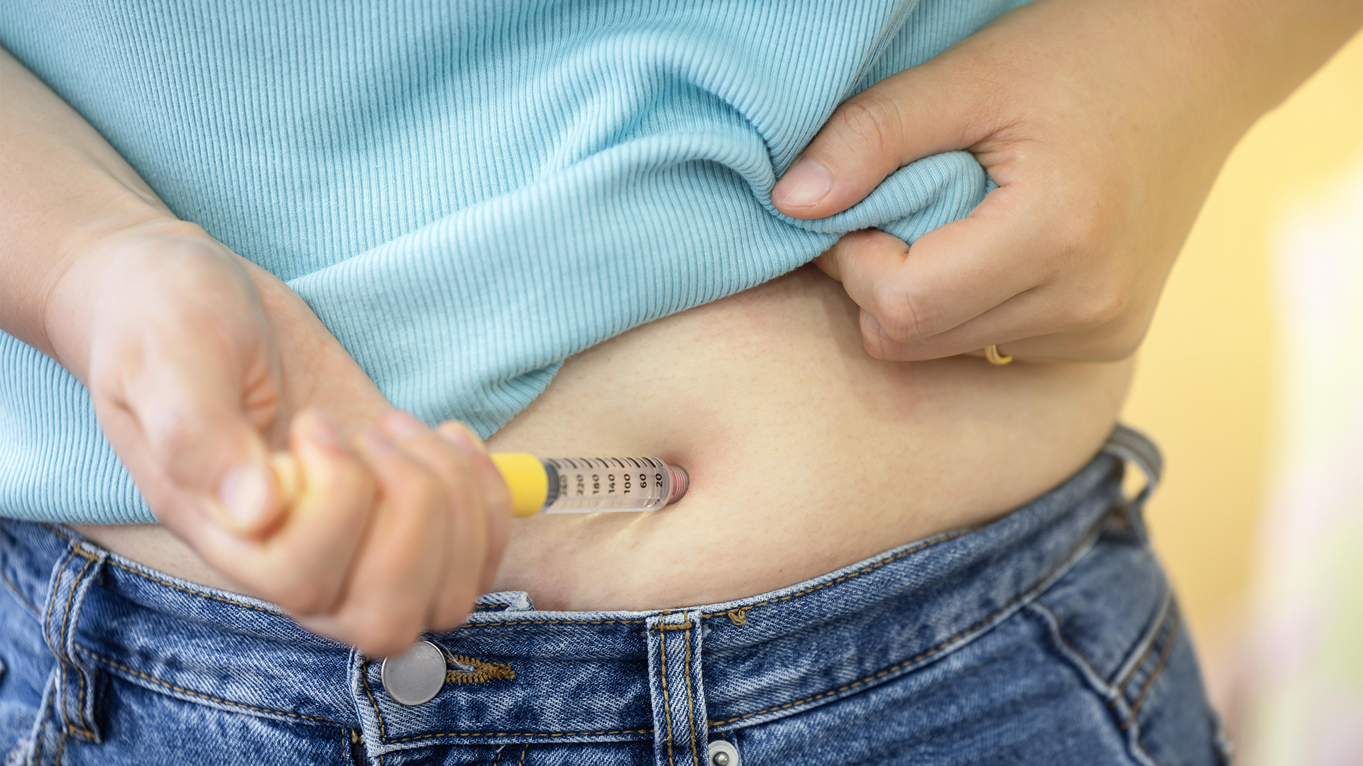 Person som håller en insulinpenna mot buken för att injicera insulin