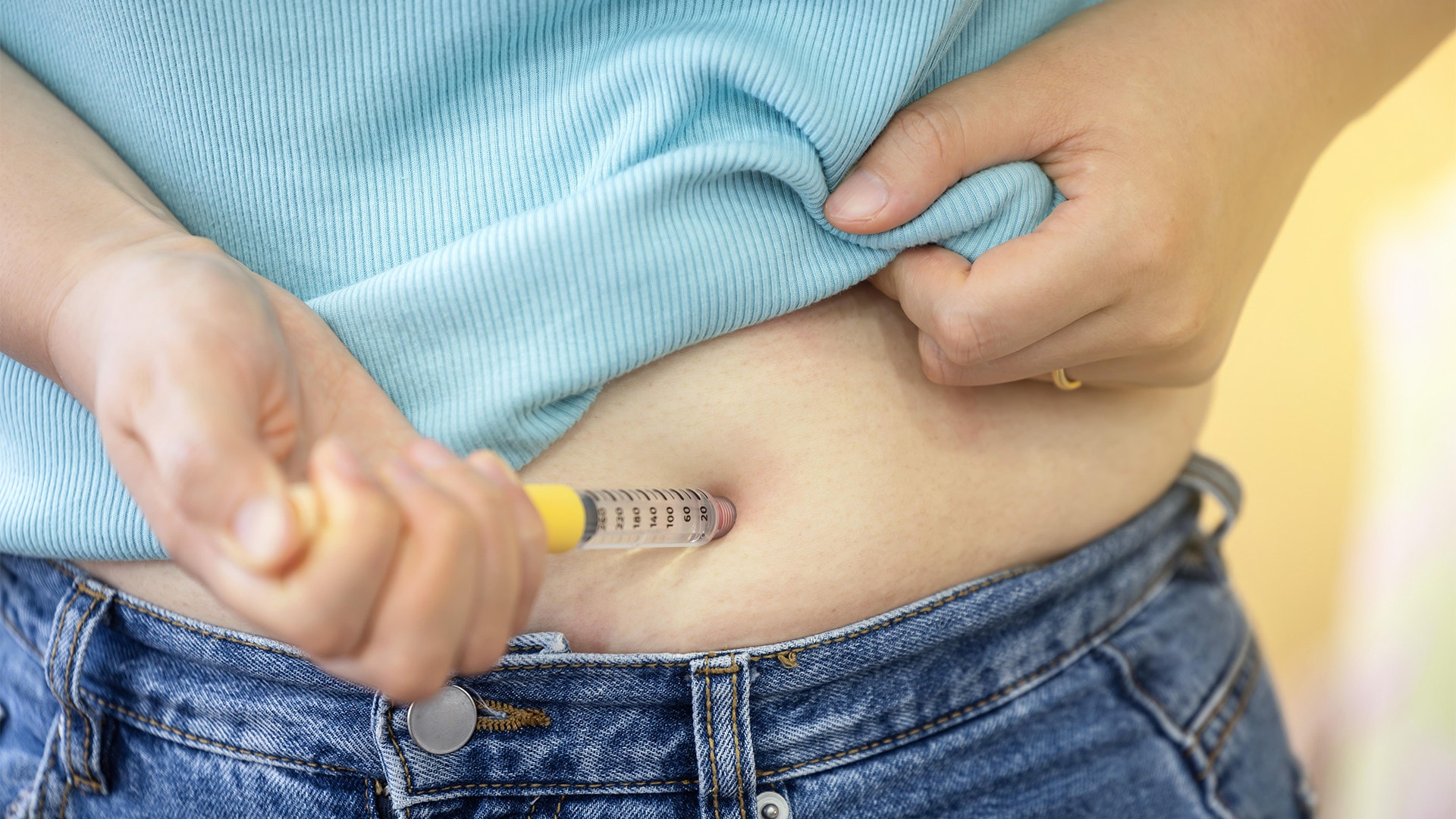 Person som håller en insulinpenna mot buken för att injicera insulin