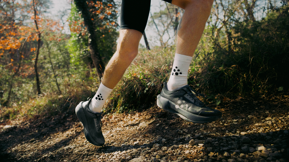 En löpare springer genom en höstig skog, klädd i Craft.