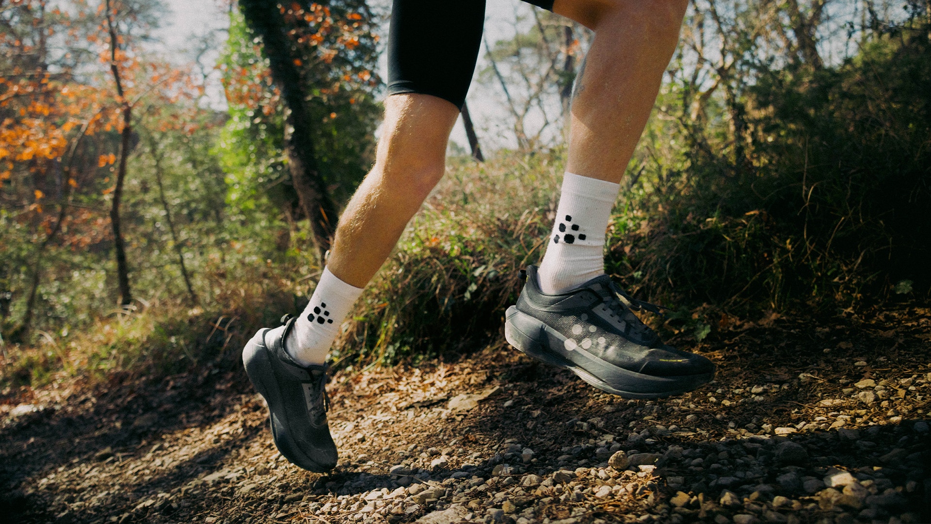 En löpare springer genom en höstig skog, klädd i Craft.