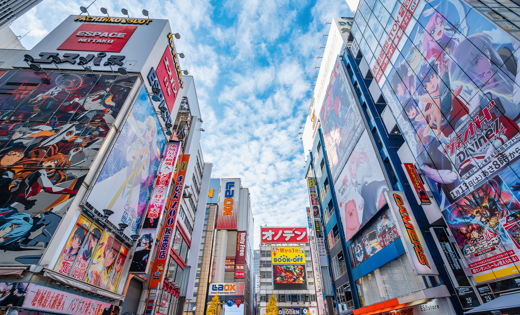 Japansk stadsgata med höga byggnader täckta av färgglada reklamskyltar och neonskyltar under blå himmel.