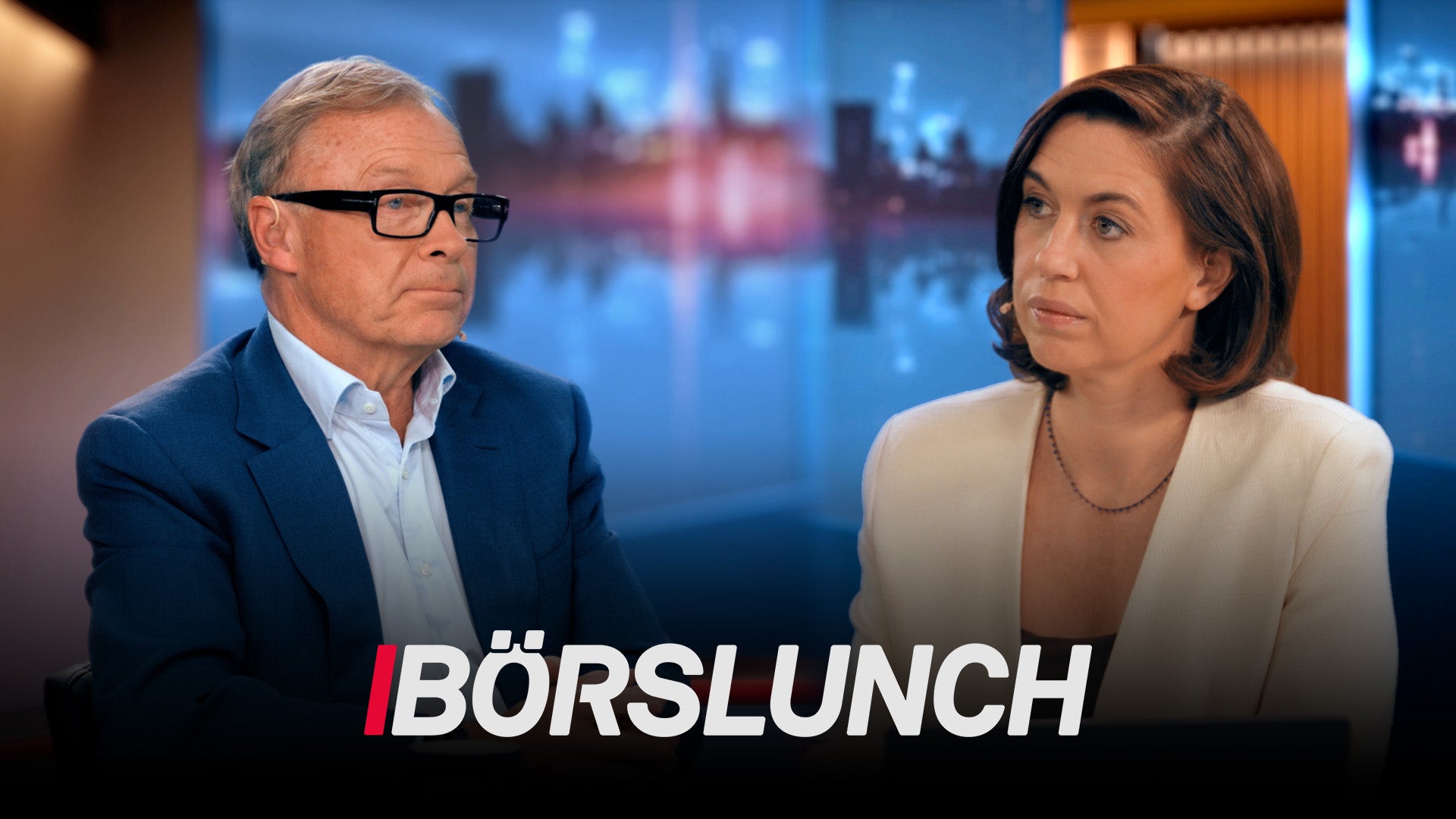 Två personer sitter vid ett studiobord med en belyst stadshorisont i bakgrunden. Texten Börslunch visas längst ned på bilden.