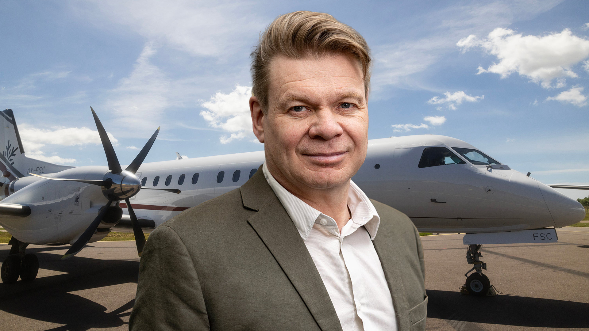 Man i kostym står framför två flygplan på en flygplats
