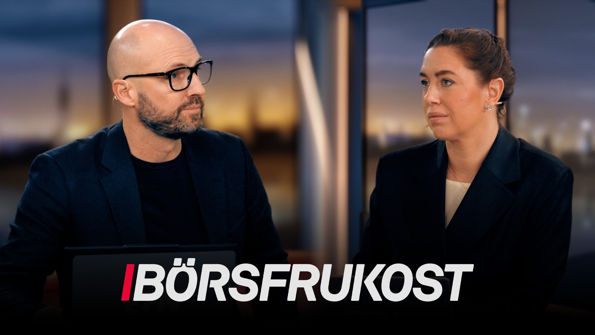 Två personer i affärskläder diskuterar vid ett möte med stadsutsikt i bakgrunden. Logotypen för Börsfrukost visas längst ned.