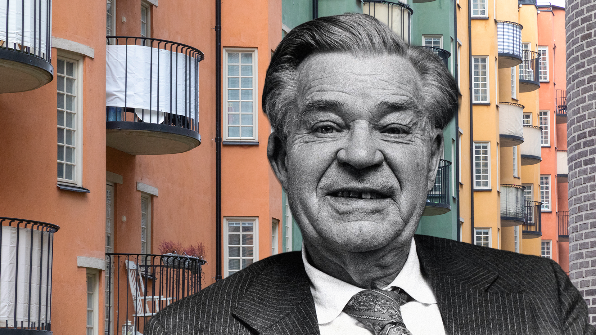 Svartvit porträttfoto av en äldre man i kostym och slips, monterad framför ett färgglatt urbant buskehus med orange, gula och gröna fasader.