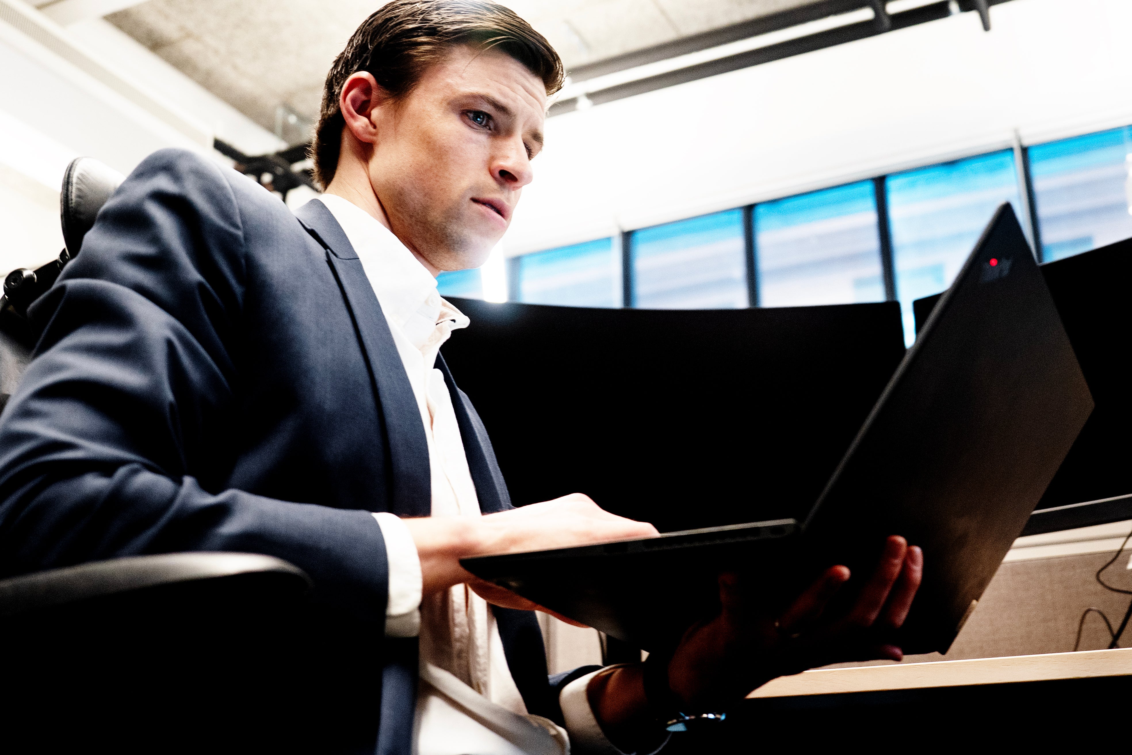 Man i kostym arbetar på laptop i modernt kontor