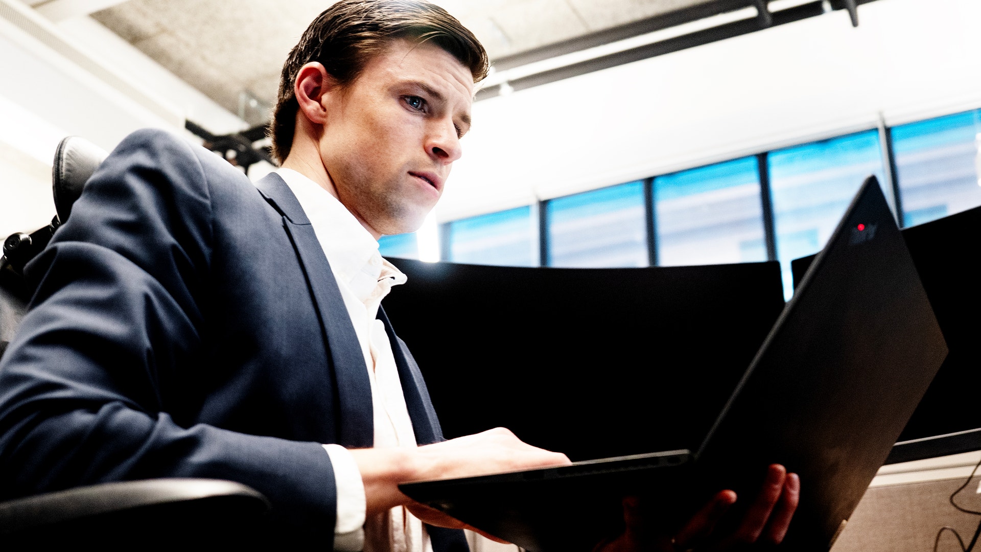 Man i kostym arbetar på laptop i modernt kontor