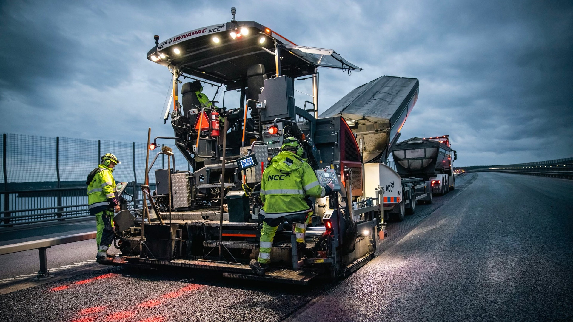 Asfalteringsmaskiner och arbetare lägger asfalt på en väg på Sundsvallsbron.