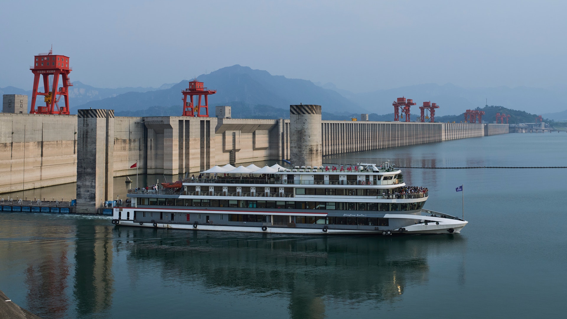 Ett kryssningsfartyg framför vattenkraftverket De Tre Ravinernas Damm i Kina