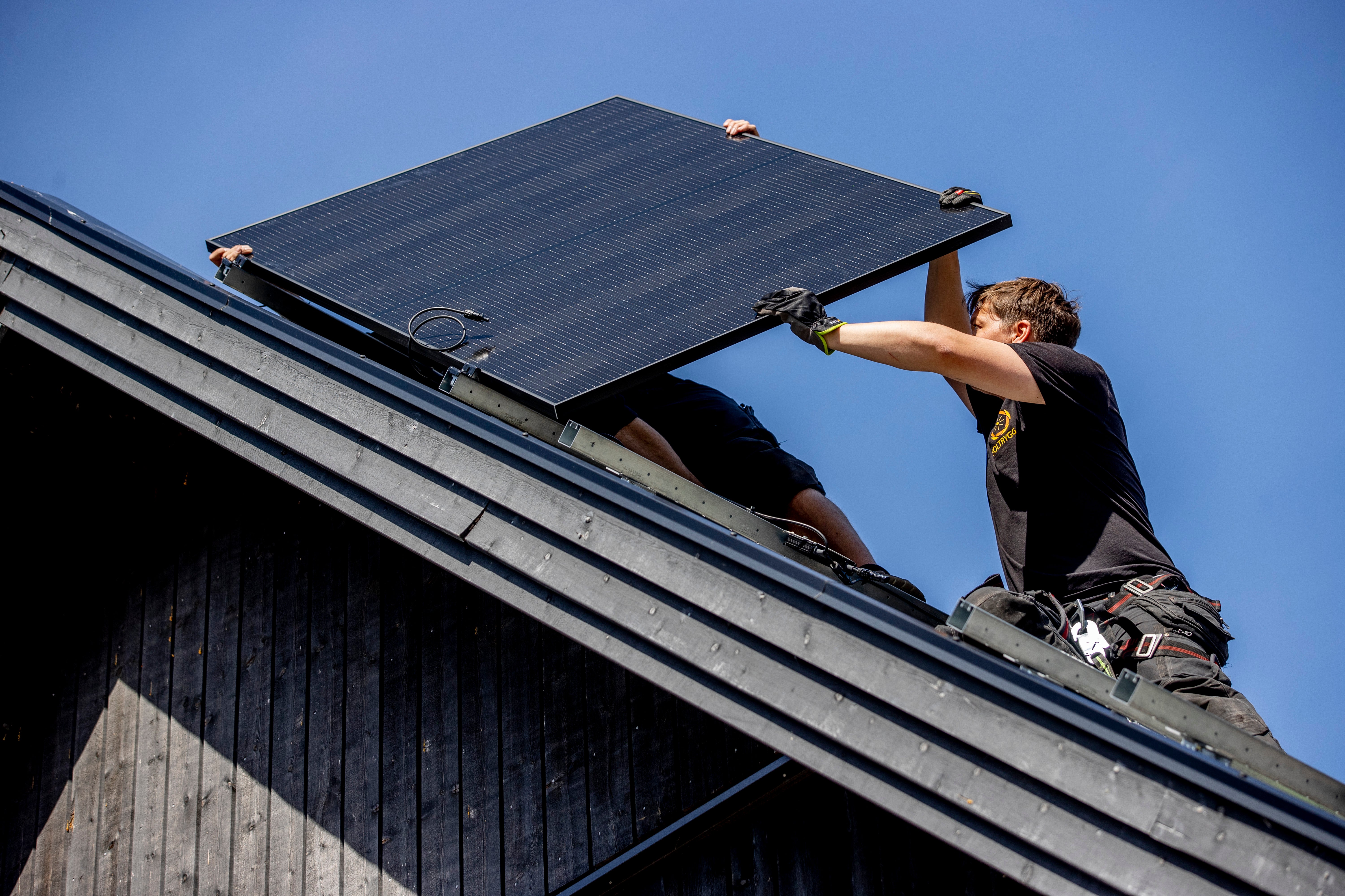 Arbetare installerar en solpanel på ett tak