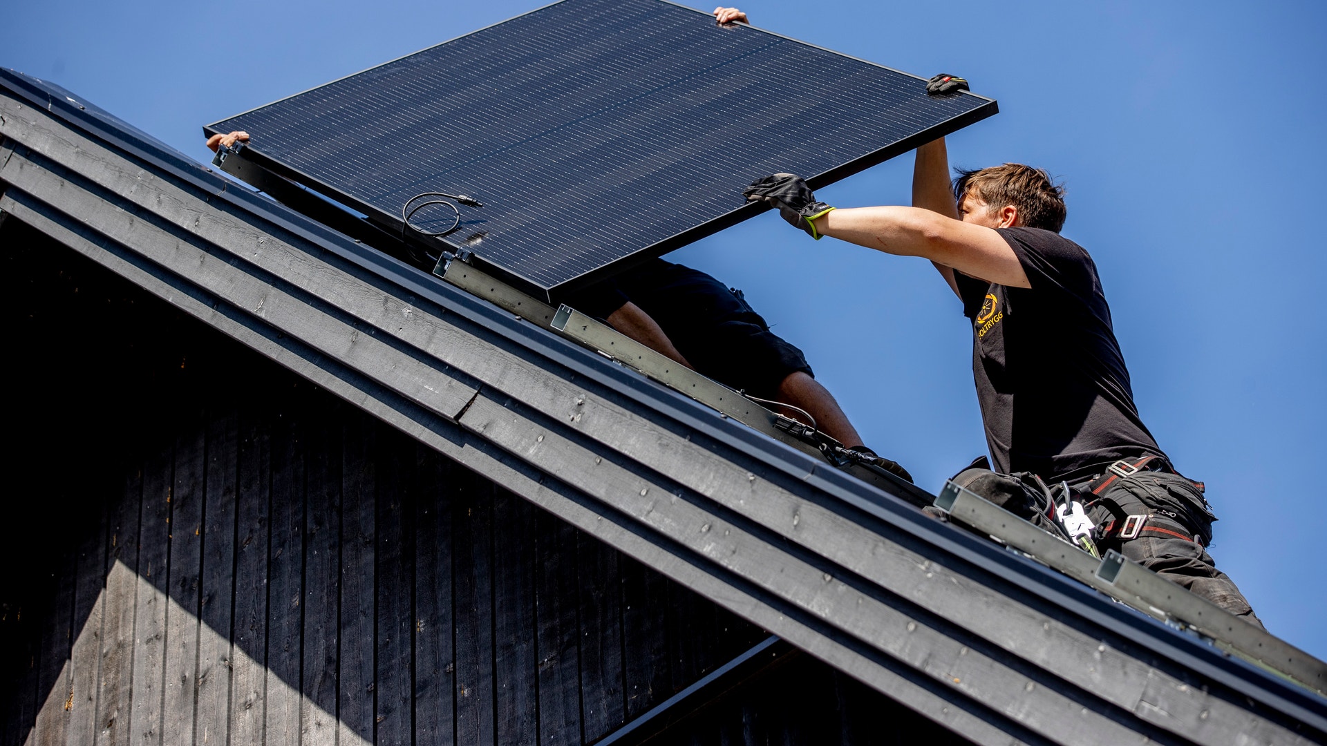 Arbetare installerar en solpanel på ett tak